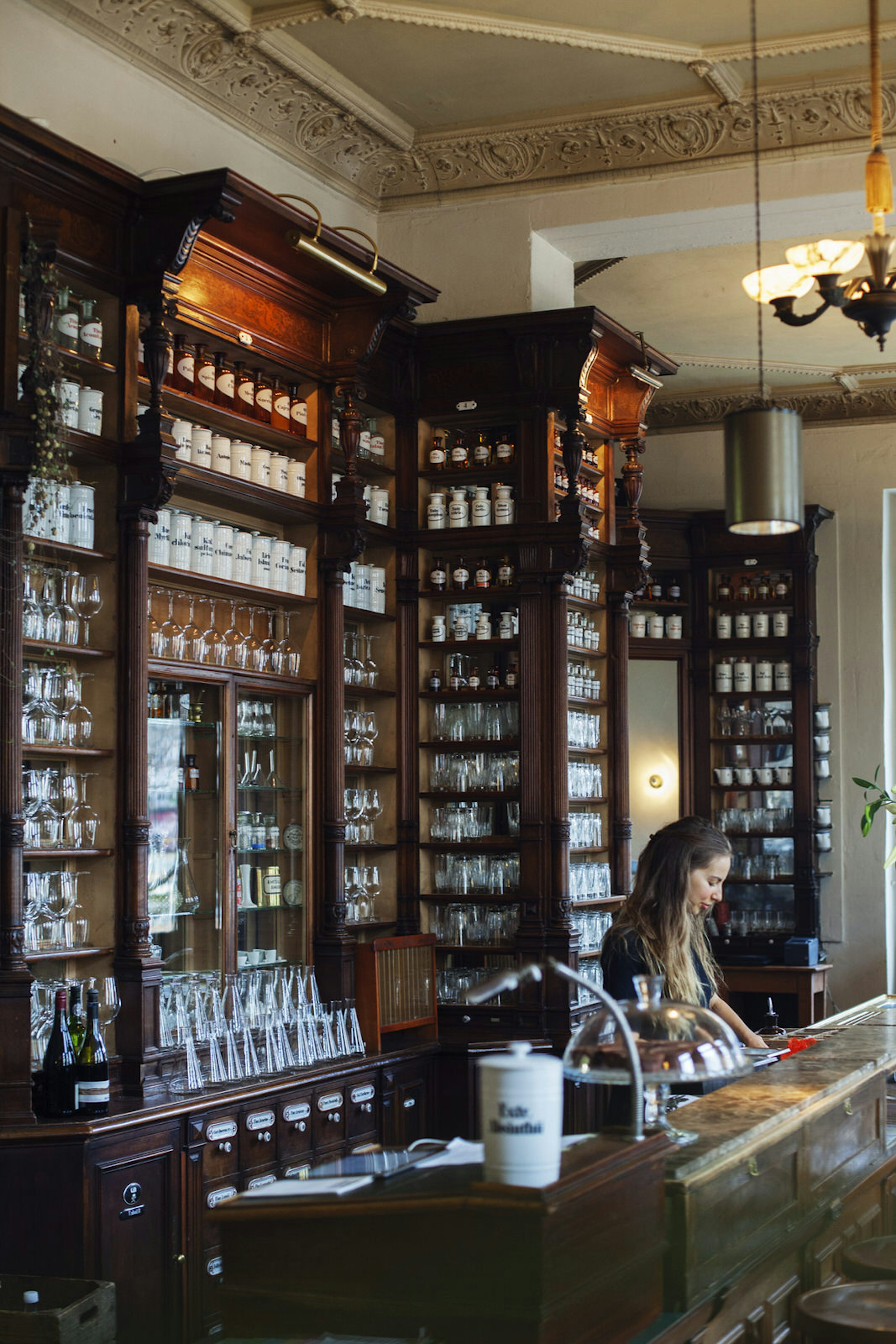 Cafe ORA's shelves are stacked to the brim with glasses, botlles and tins of different teas and coffees, surround by dark-stained wooden furniture - Lonely Planet © ORA