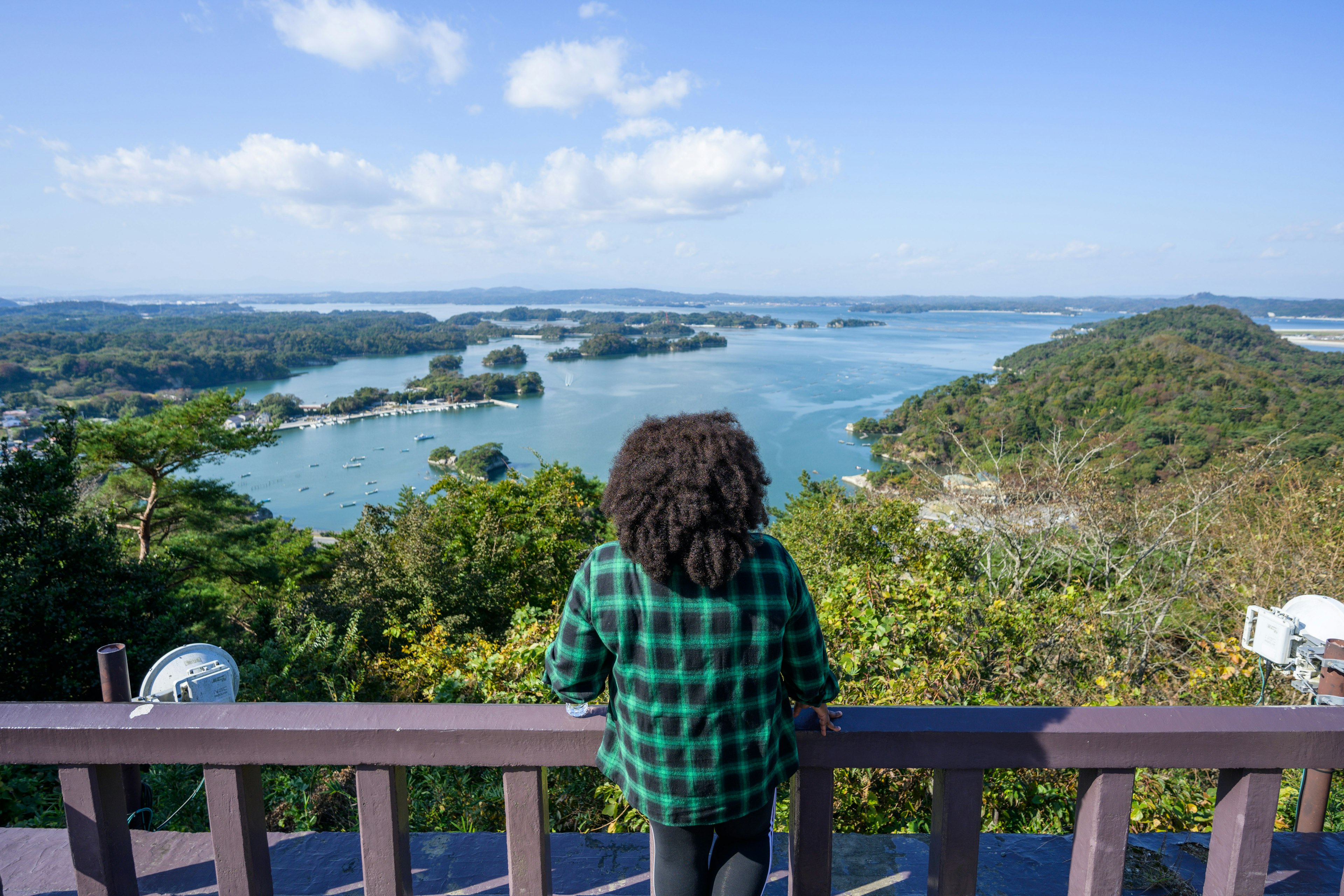 A woman looks over Masushima Bay from a hill top.