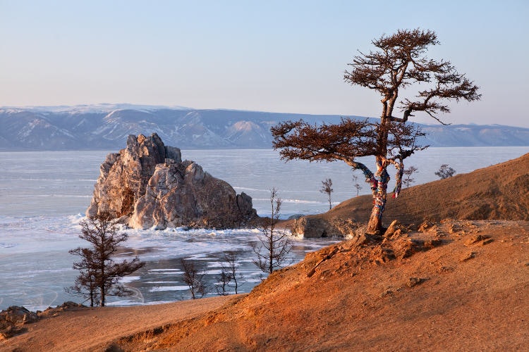 A large rock formation on the edge of a very big lake