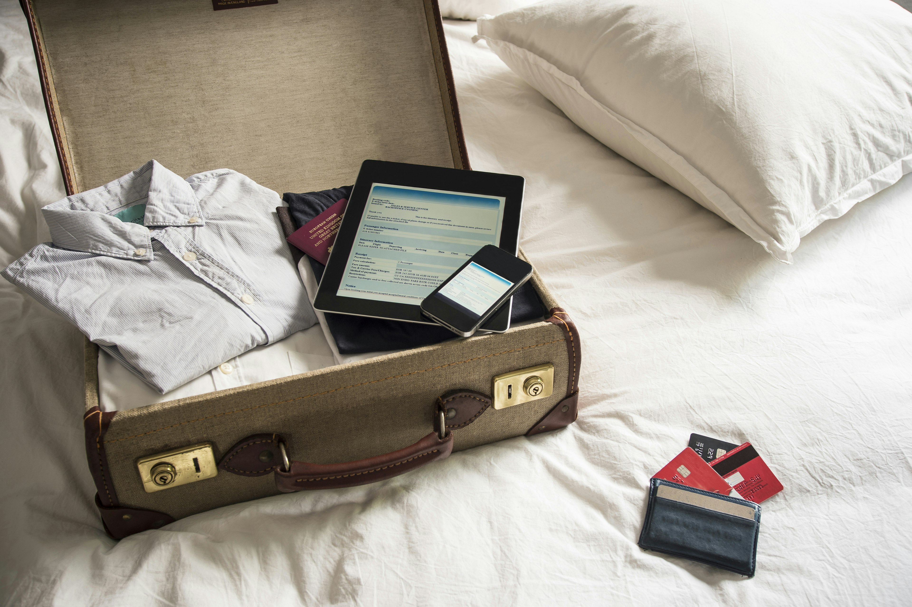 An open suitcase, with iPad, phone and passport inside