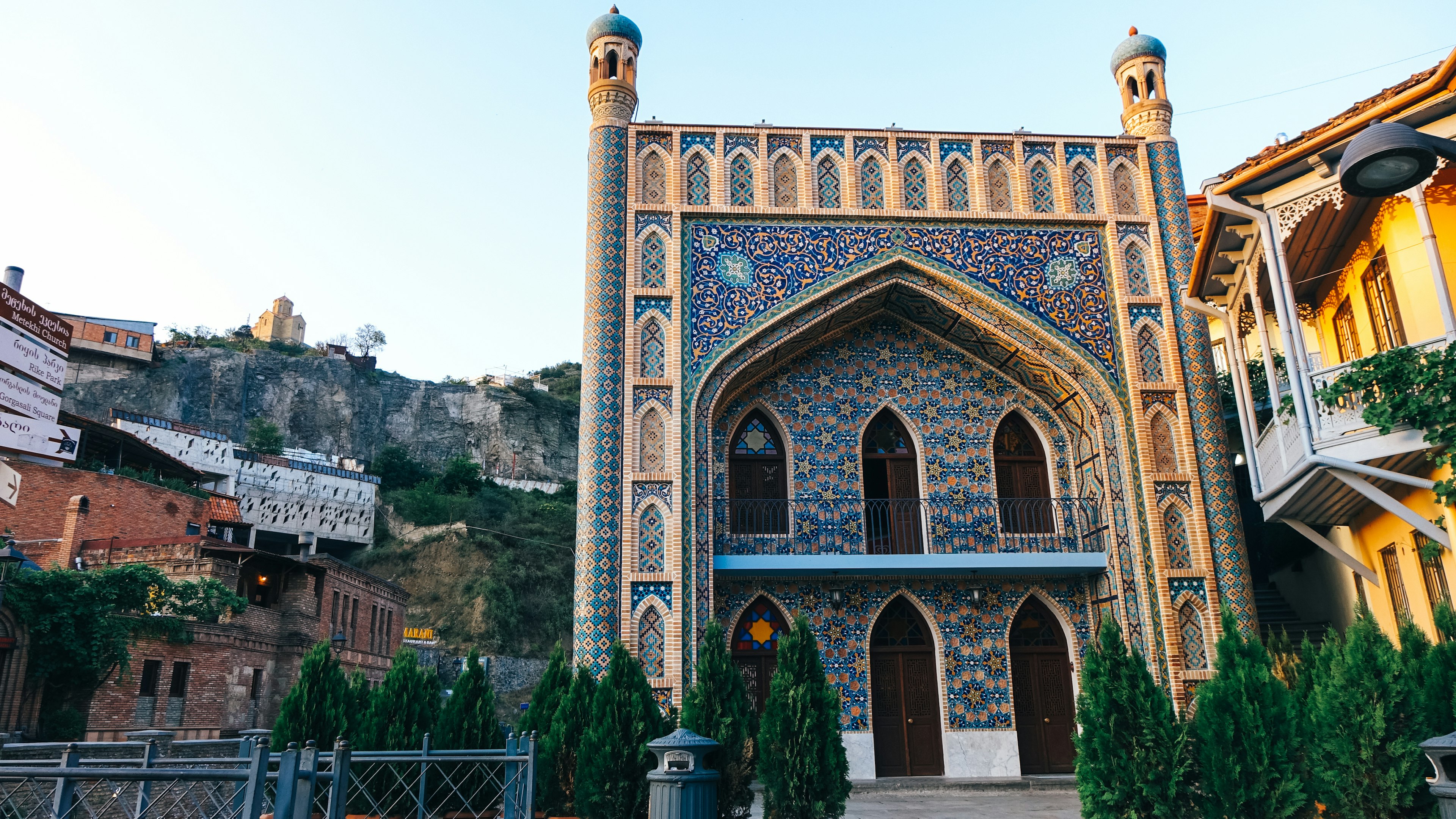 The ornate facade of the Chreli Abano (Orbeliani) sulphur baths in Tbilisi; it's entirely covered in blue and yellow tiles and there are arched doors, as well as minarets on each corner.