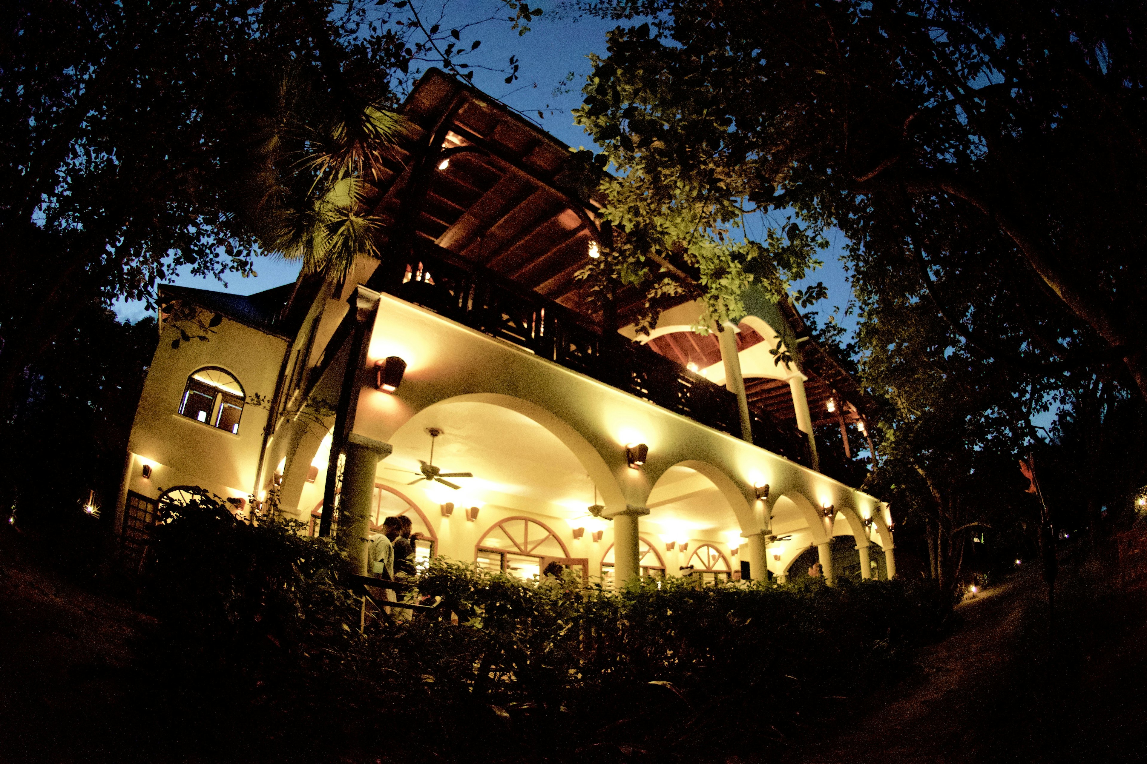 The Colonial-style lodge at Hamanasi, at dusk. Trees are visible in front of and behind the building.