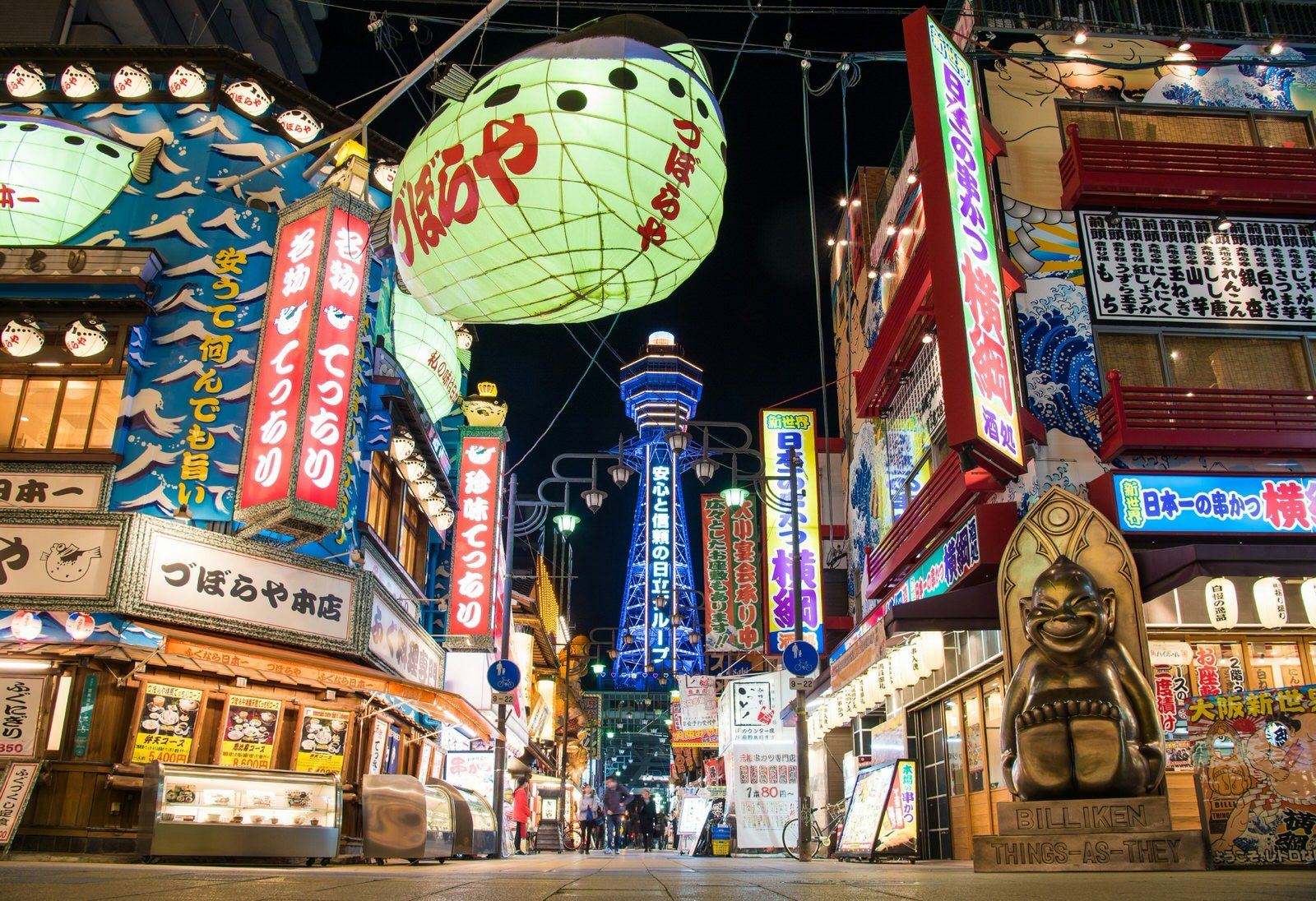 Bright shopfronts light up the night in Osaka – Tsutenkaku Tower is visible in the background