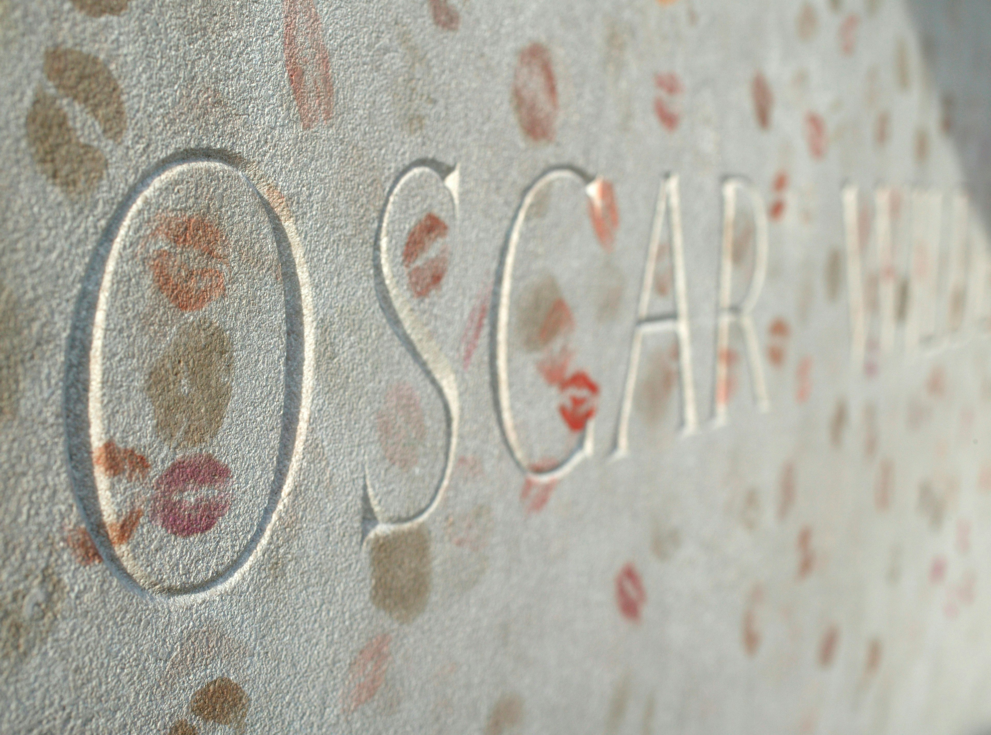 A close-up of the words 'Oscar Wilde' taken from the poet's tomb in Paris, covered in lipstick kiss marks from visitors.