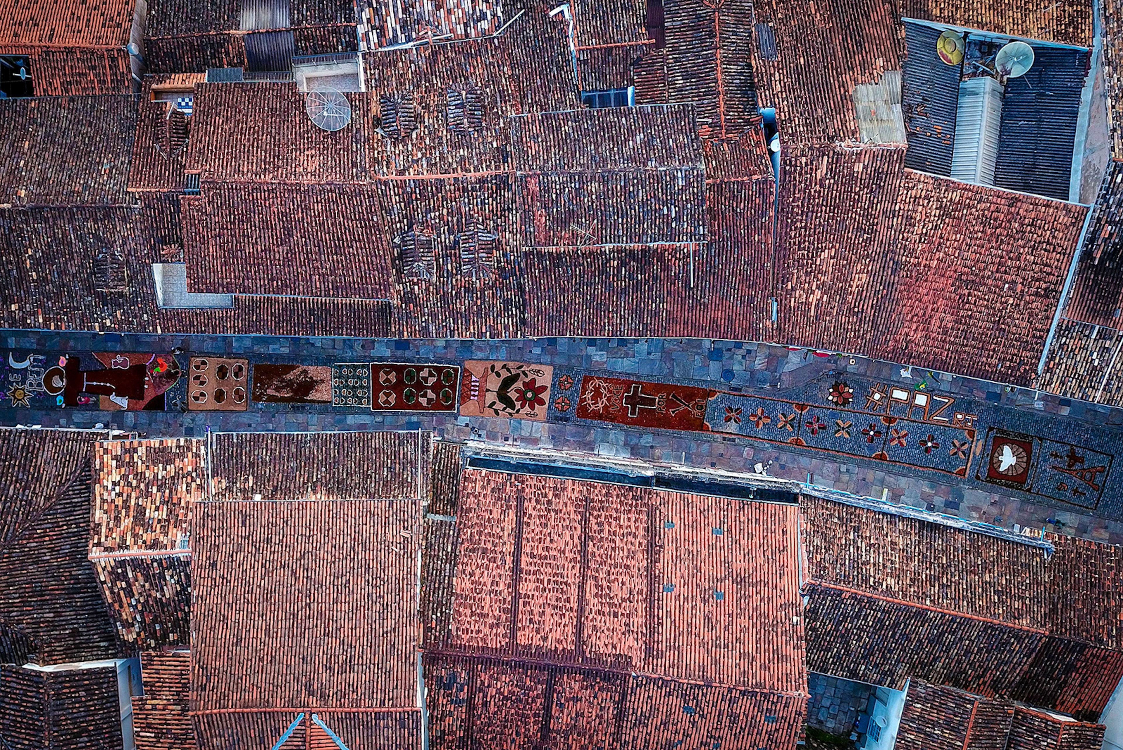 Aerial picture showing sawdust rugs, seen between tiled rooftops, decorating a street in the historic city of Ouro Preto in Brazil during Easter