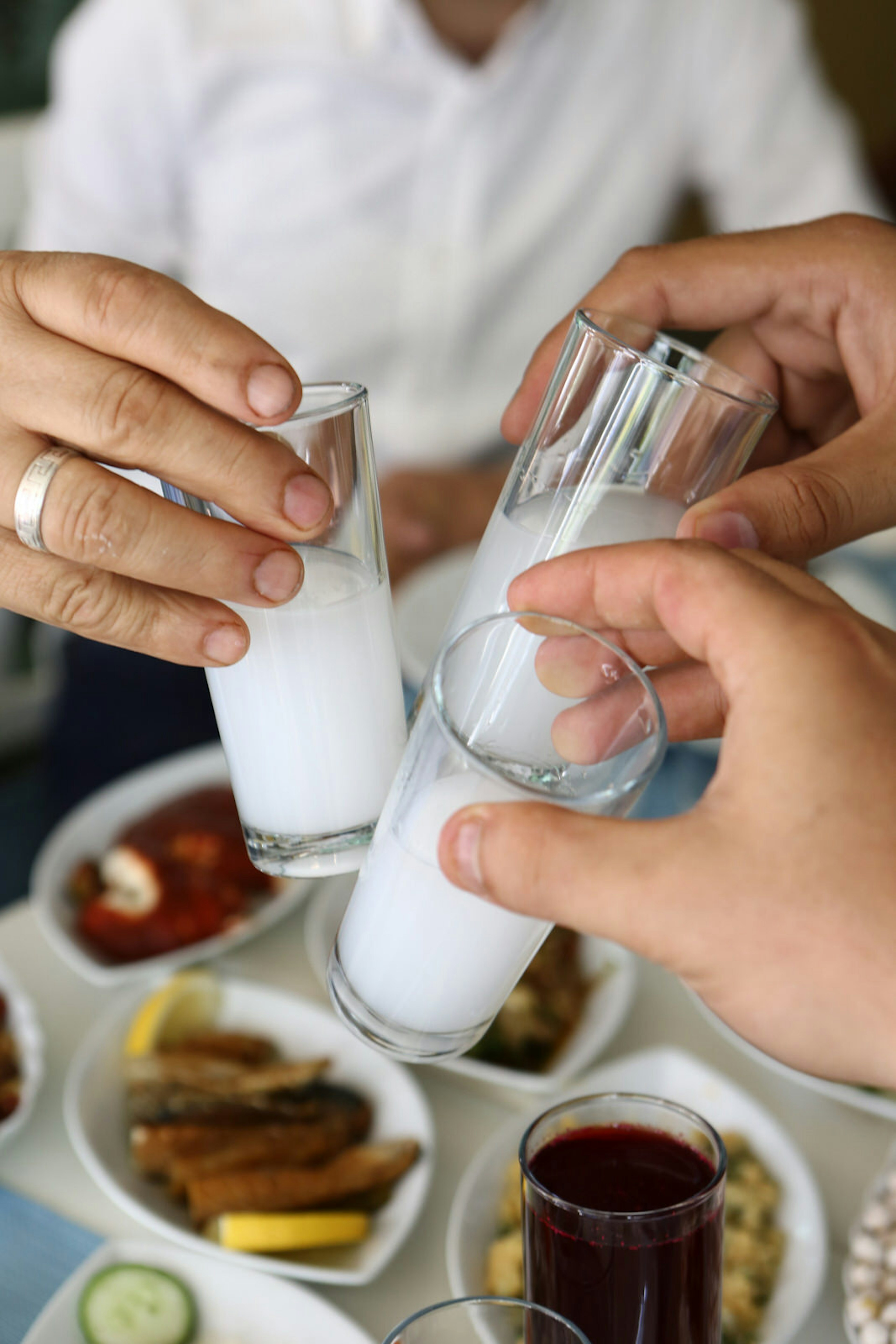 People clinking shot glasses of ouzo