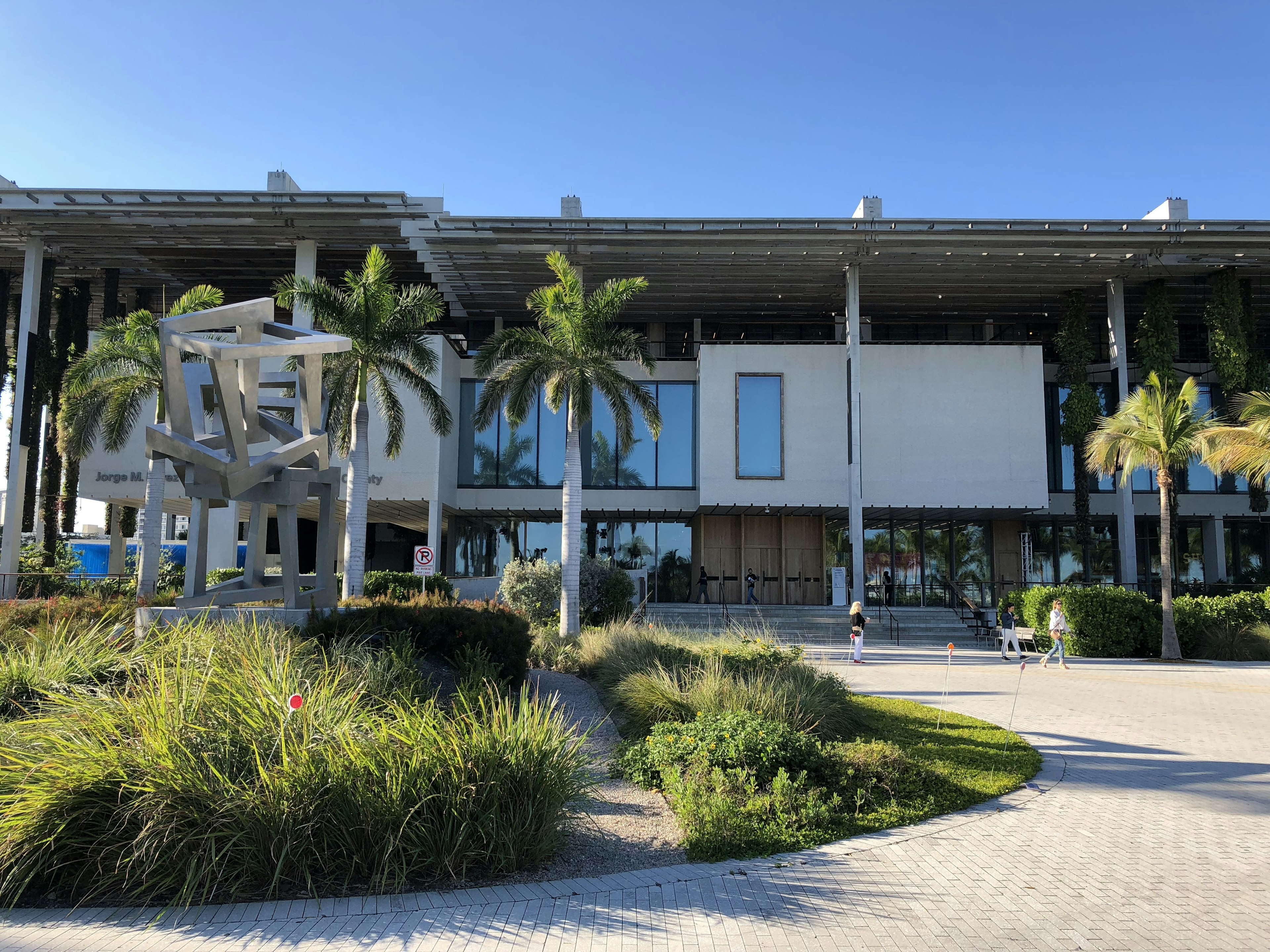 A striking buidling, with square modules in a modern style with white walls, is seen, with palm trees and tropical grasses in the foreground © Jackie Gutierrez-Jones / Lonely Planet