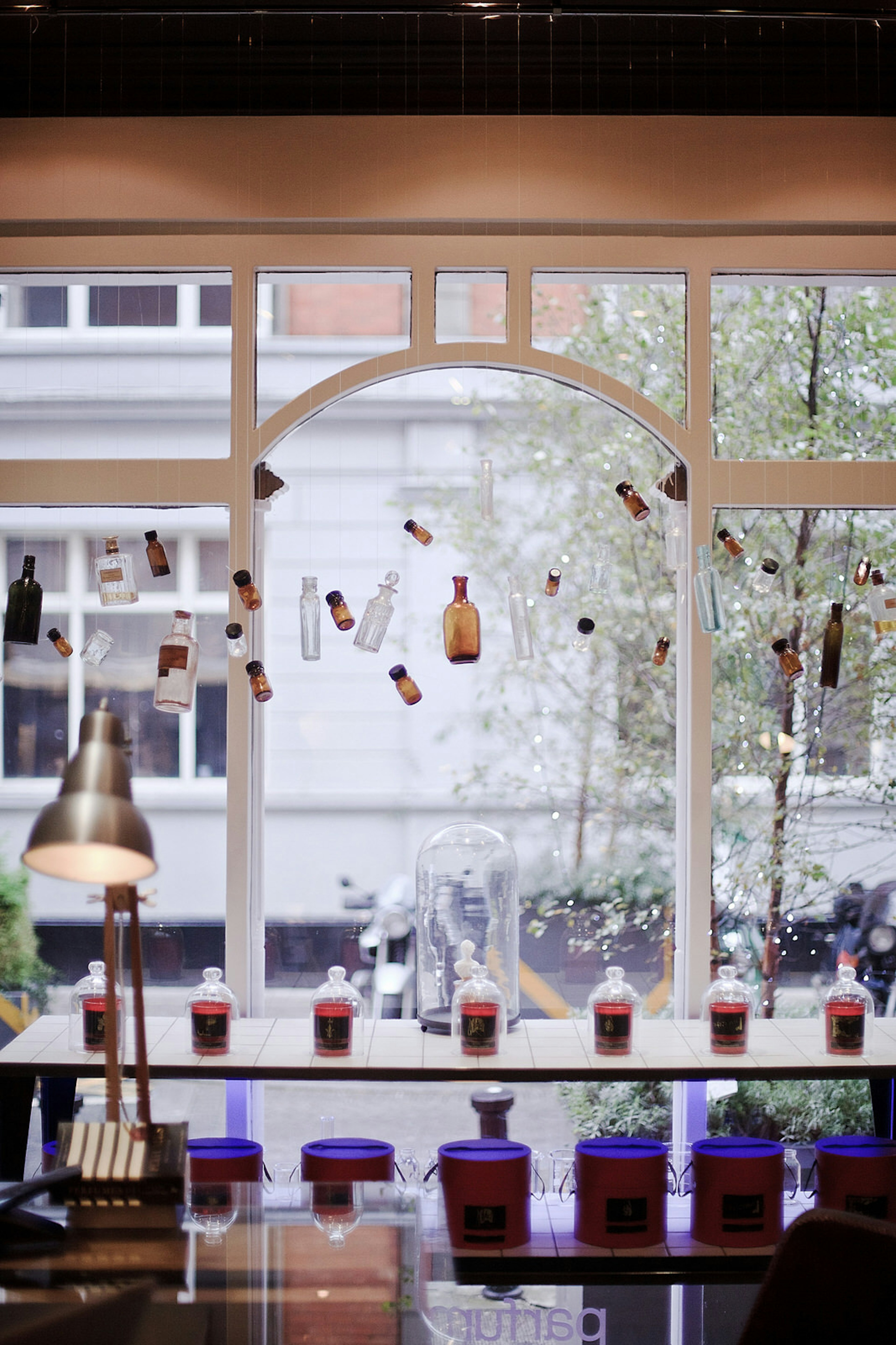 Dublin independent shops - Parfumarija's window display with brown bottles of different sizes dangling at a variety of heights in a lovely arched window with white frames. There is a shelf of bottles neatly arranged in the foreground