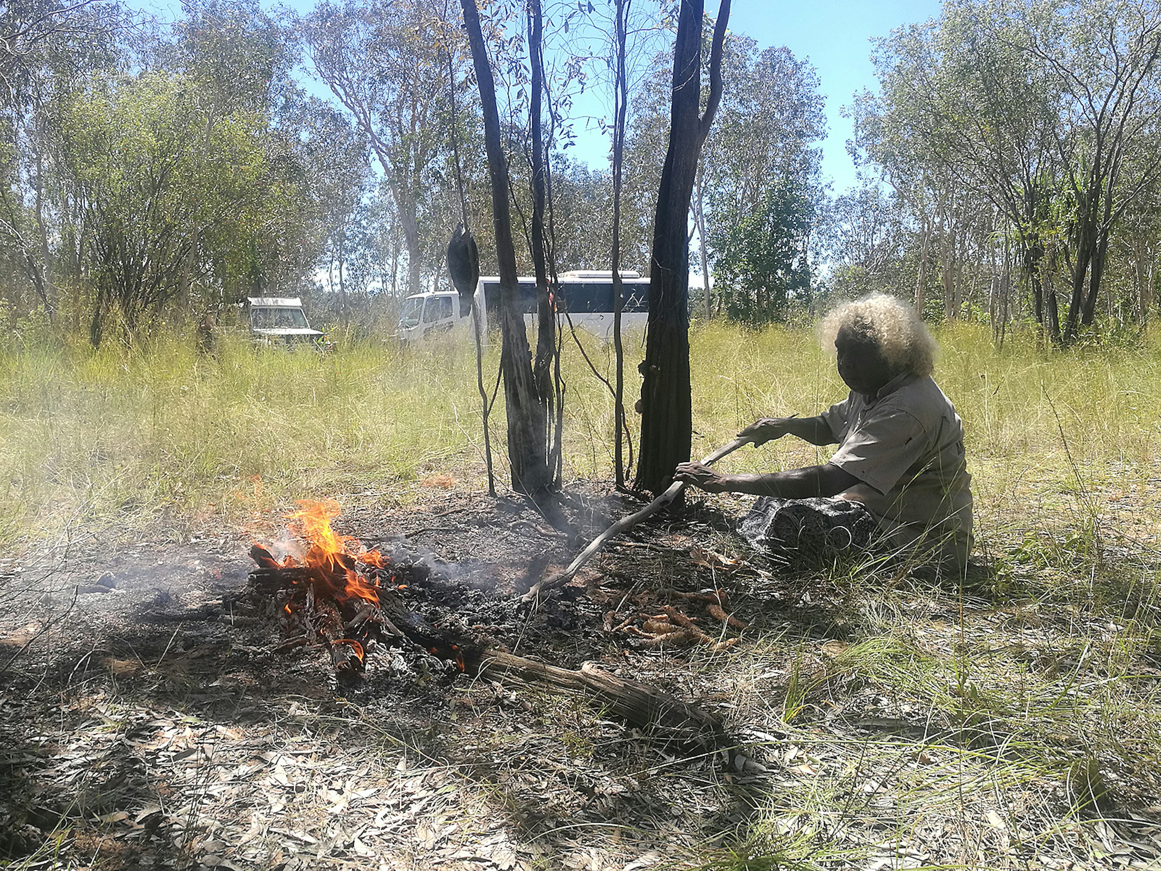 Patsy Raglar cooking a barramundi over a fire in the bush