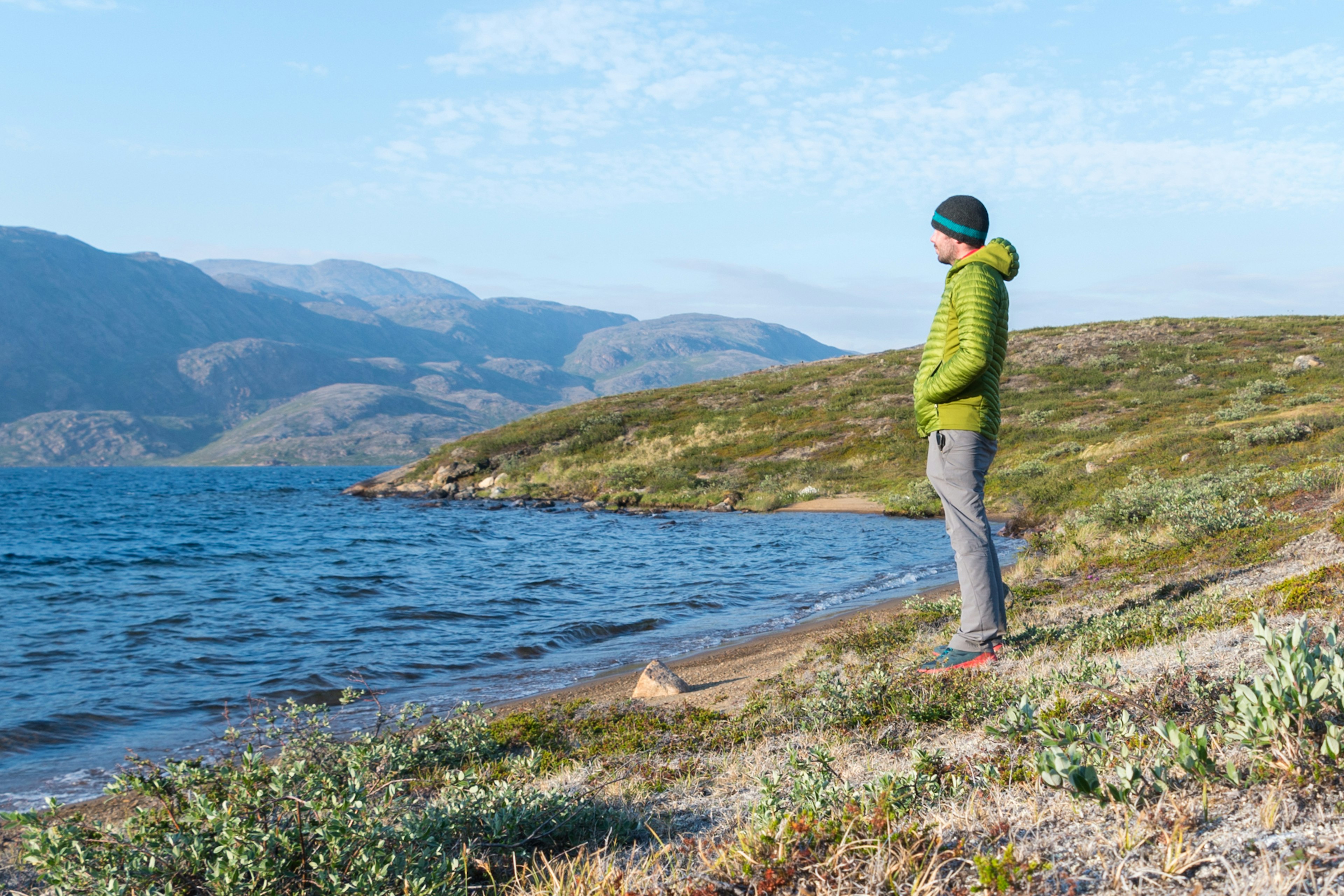 Writer Peter stands looking out over a lake, with beautiful mountain scenery in the background.