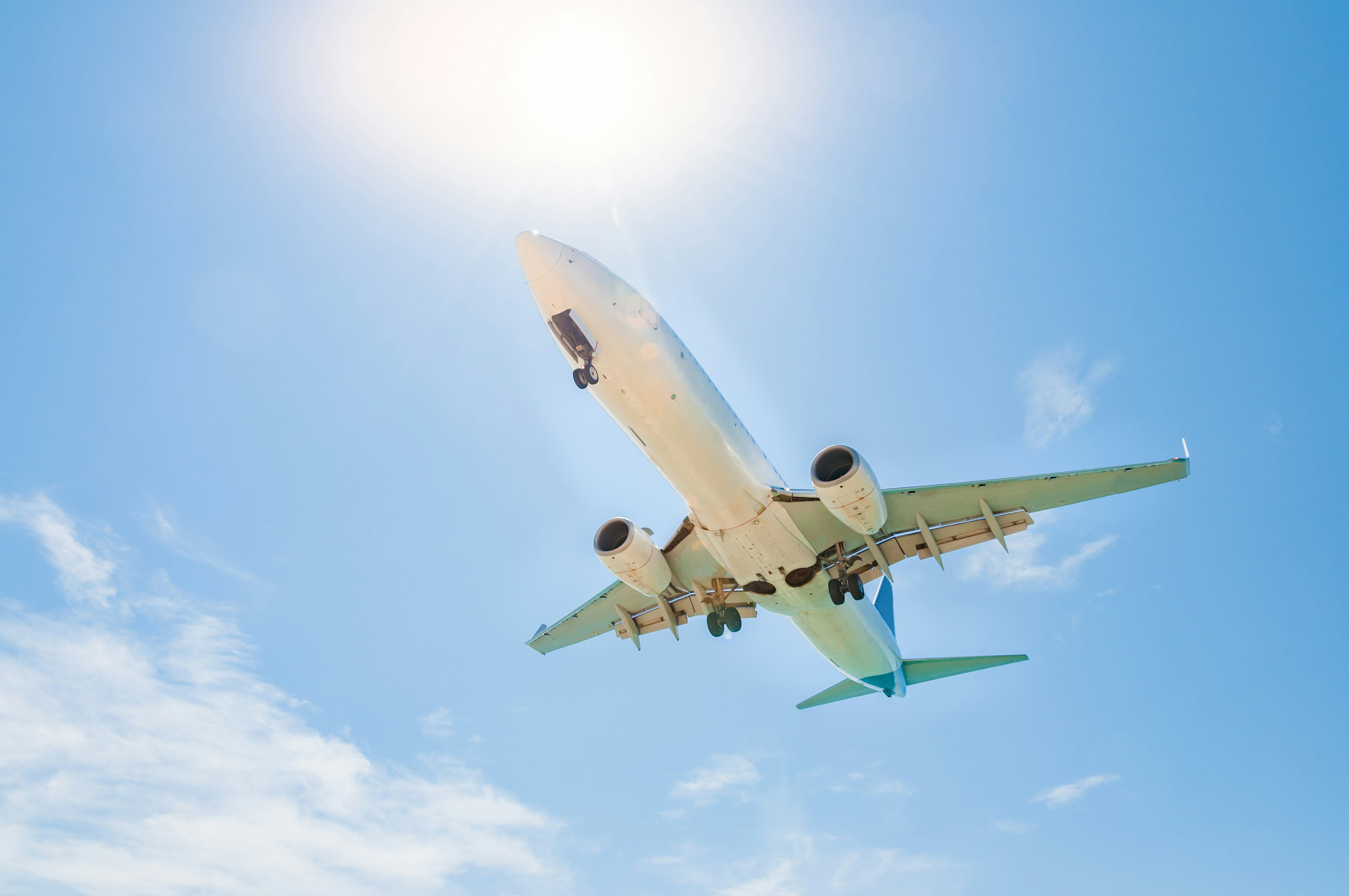 Airplane is about to landing at the airport with some flare from the bottom view