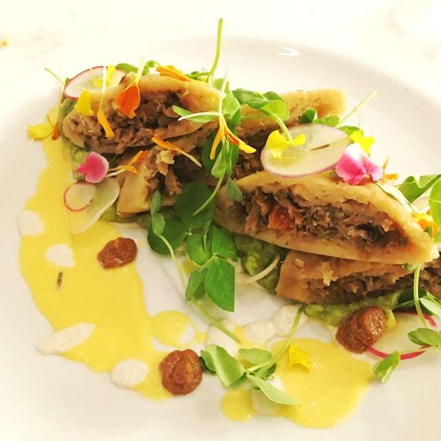 A plate of papusas garnished in green herbs and slivers of radishes with a drizzle of olive oil in the front of the plate; vegan restaurants Miami