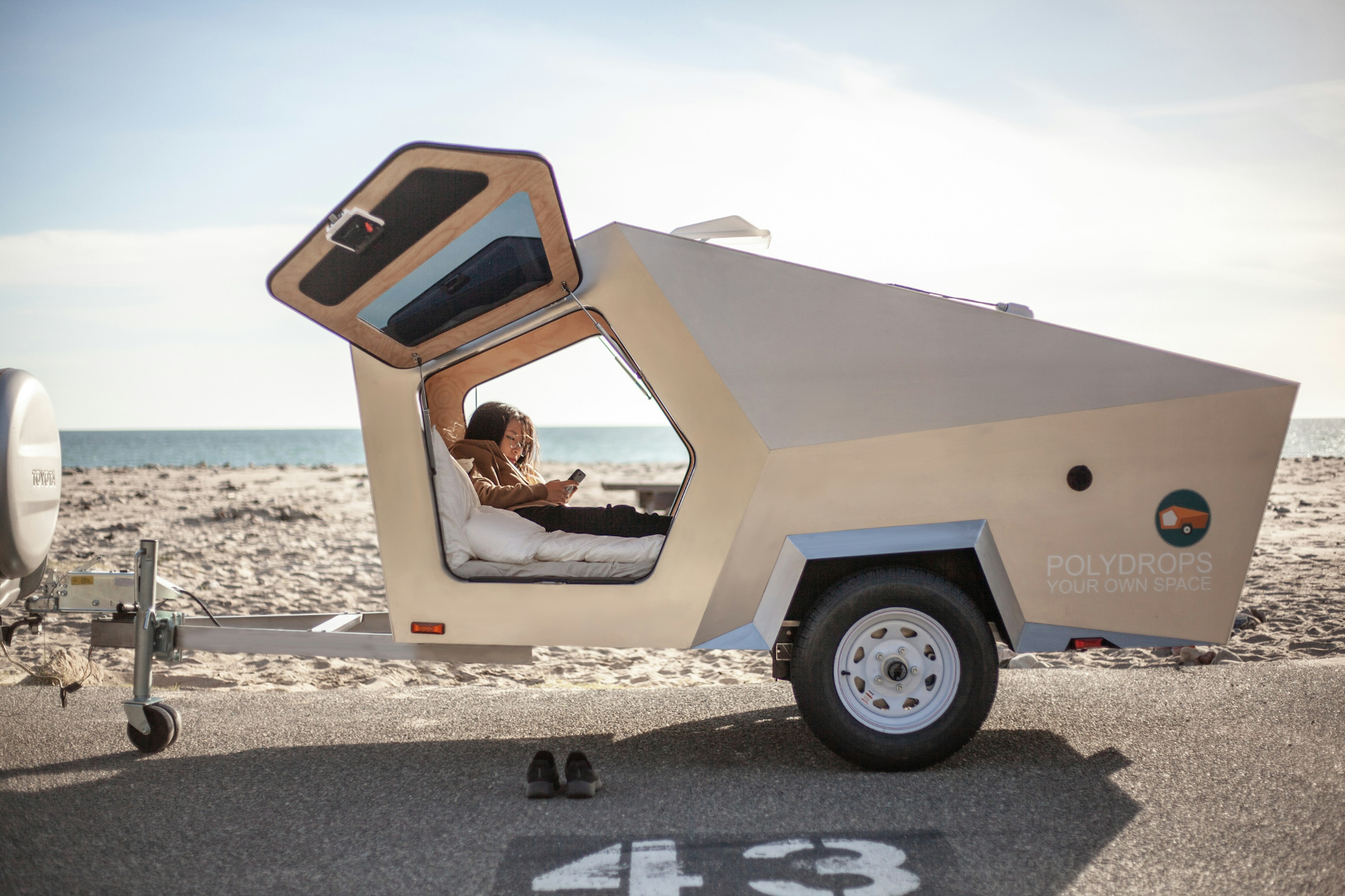 A woman sites in a small trailer near the beach.