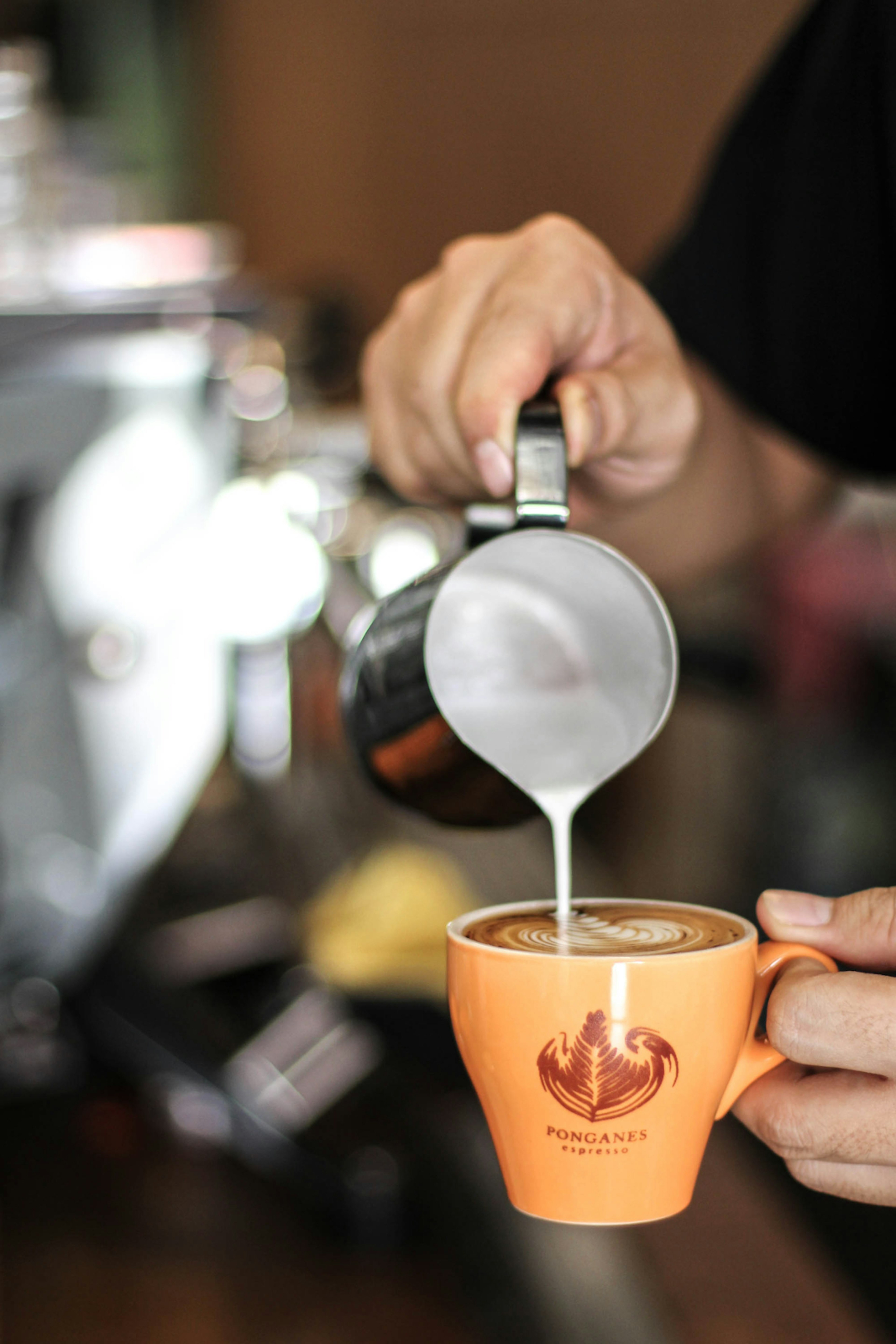 A barista pours latte art at Ponganes Coffee Roasters in Chiang Mai, Thailand