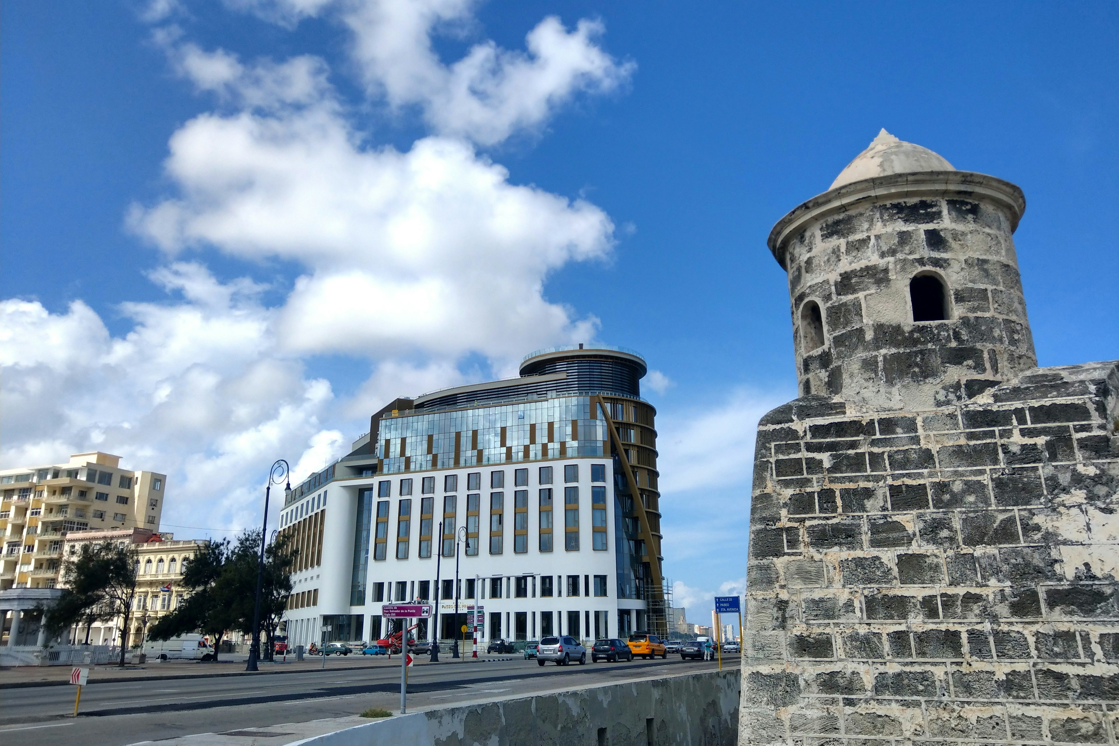 Exterior view of the glass and slate structure of the Hotel Prado in Havana. In the foreground and to the right is a tall brick structure; Historic Havana sites