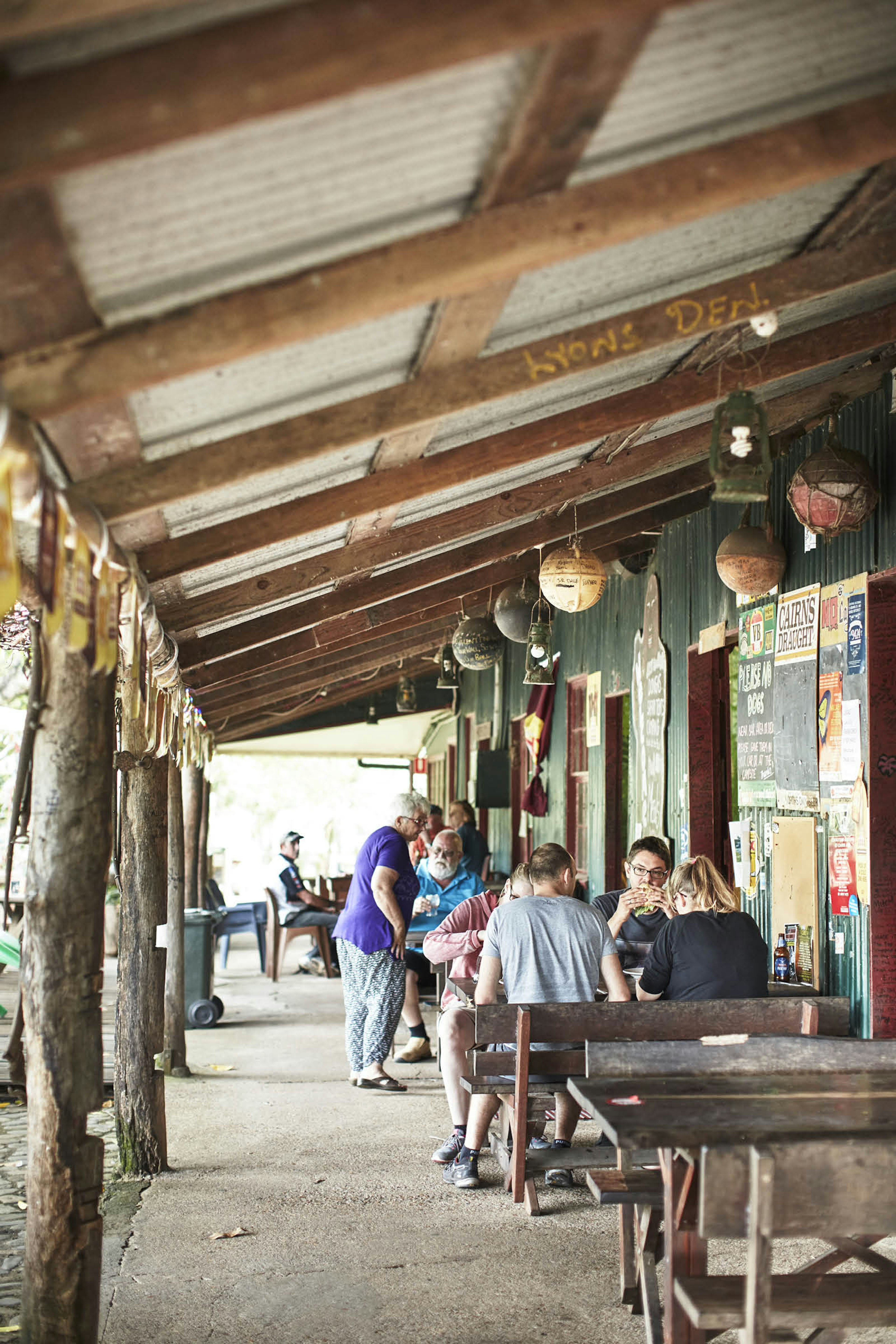 Diners at tables under the tin roof of the Lion's Den Hotel