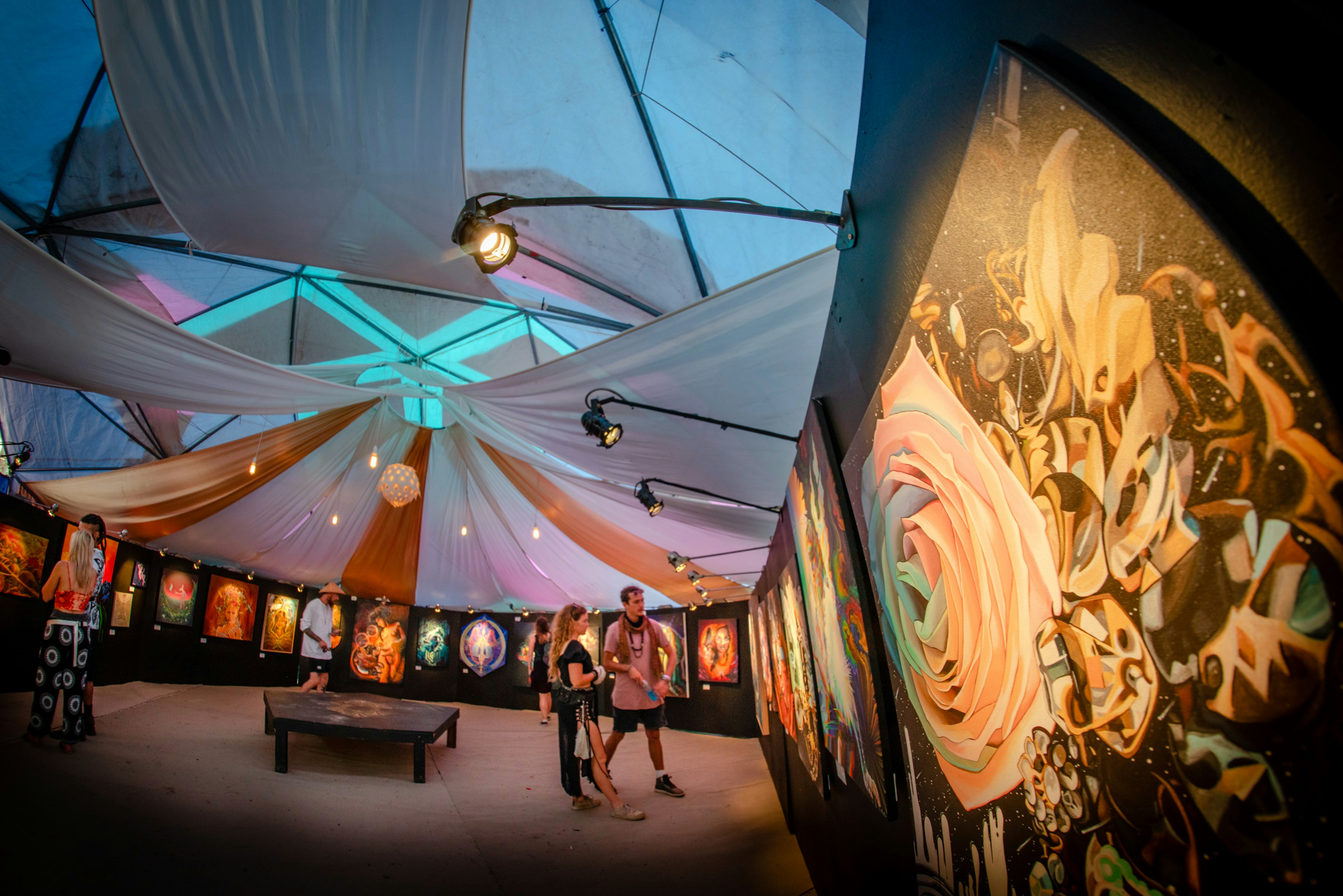 Two people stand admiring vibrant graffiti-style art on display at Rainbow Serpent Festival in Lexton, Victoria Australia.