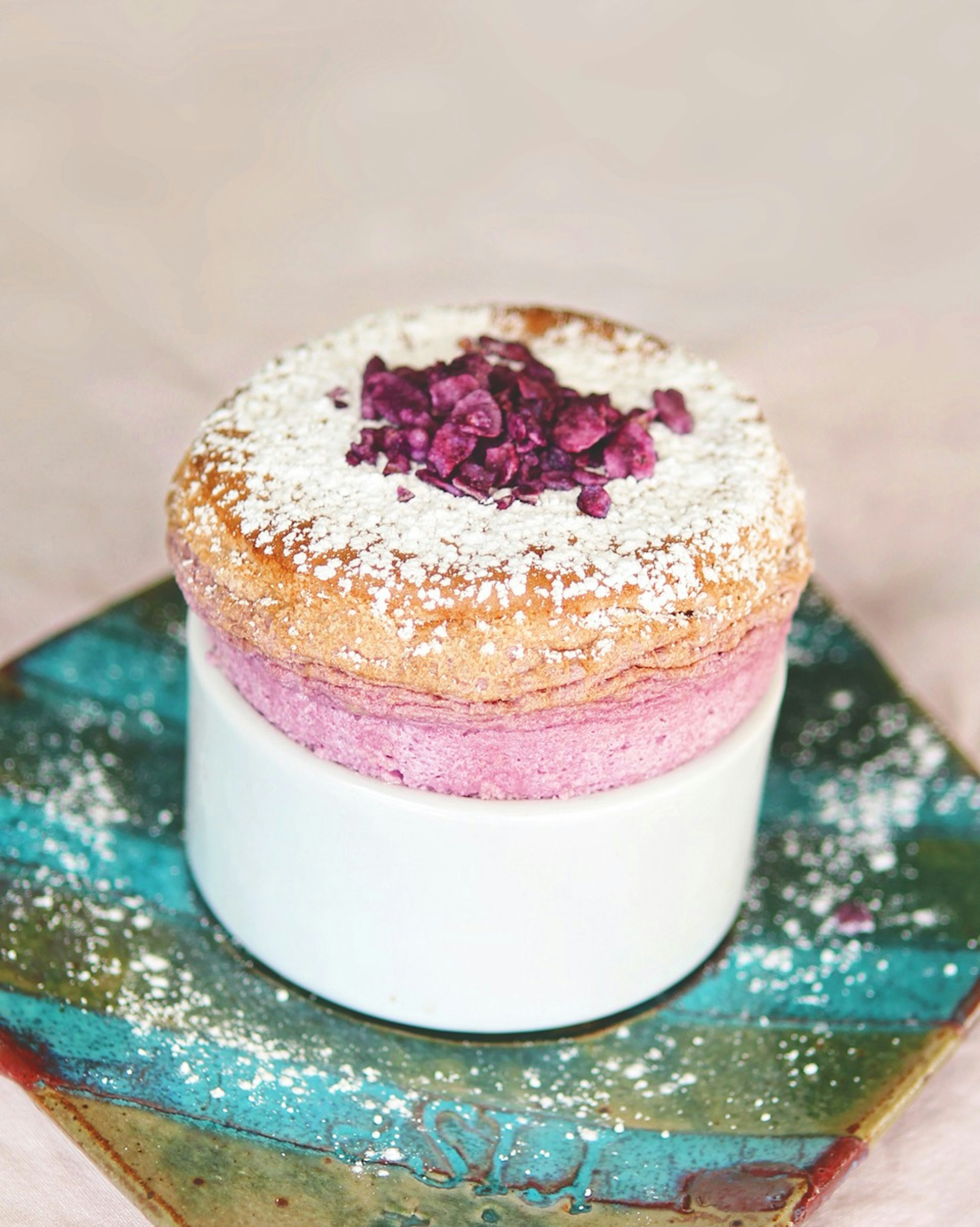 A violet souffle topped with berries and powdered sugar