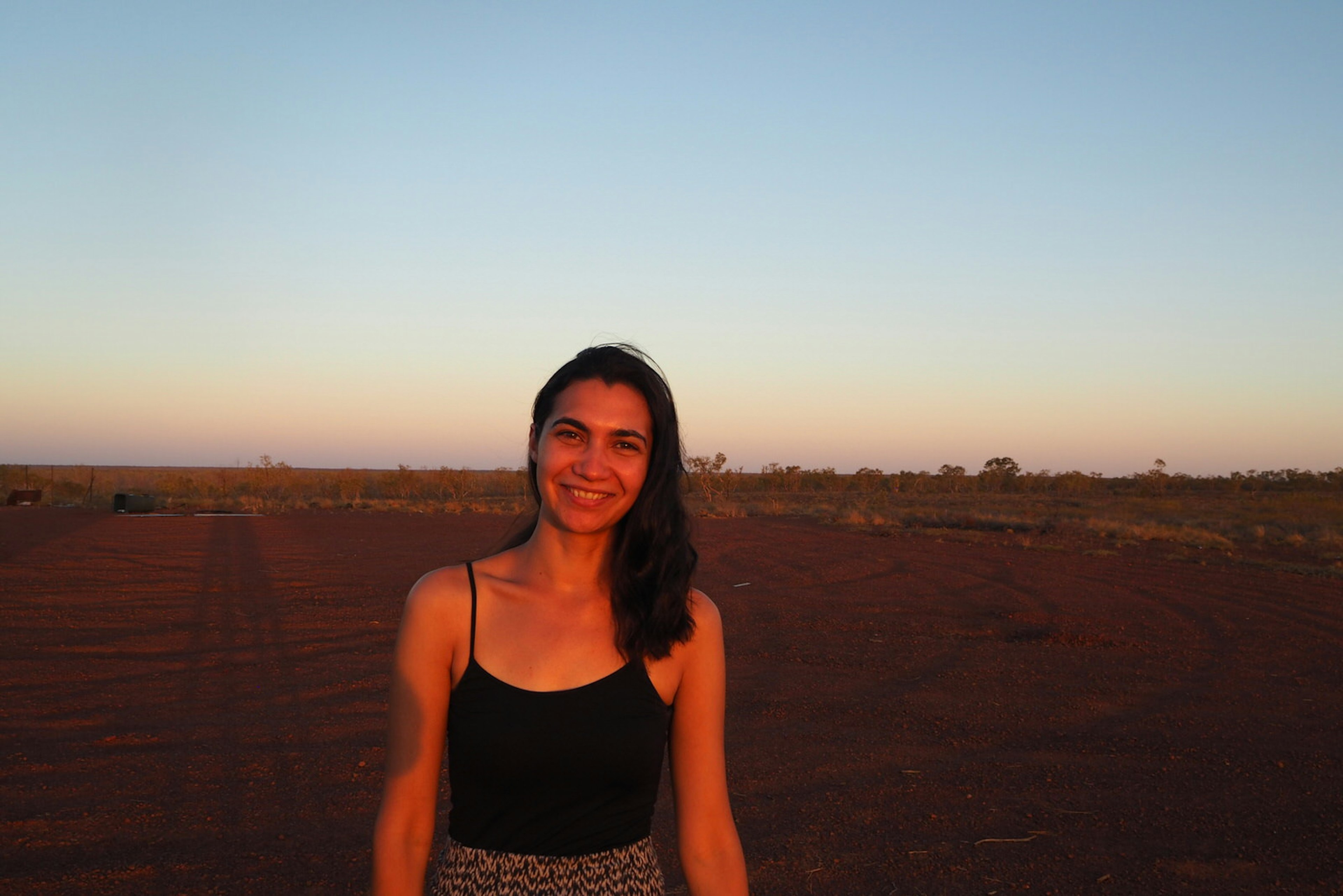 Writer Rachael Hocking smiles at the camera, standing on Warlpiri land