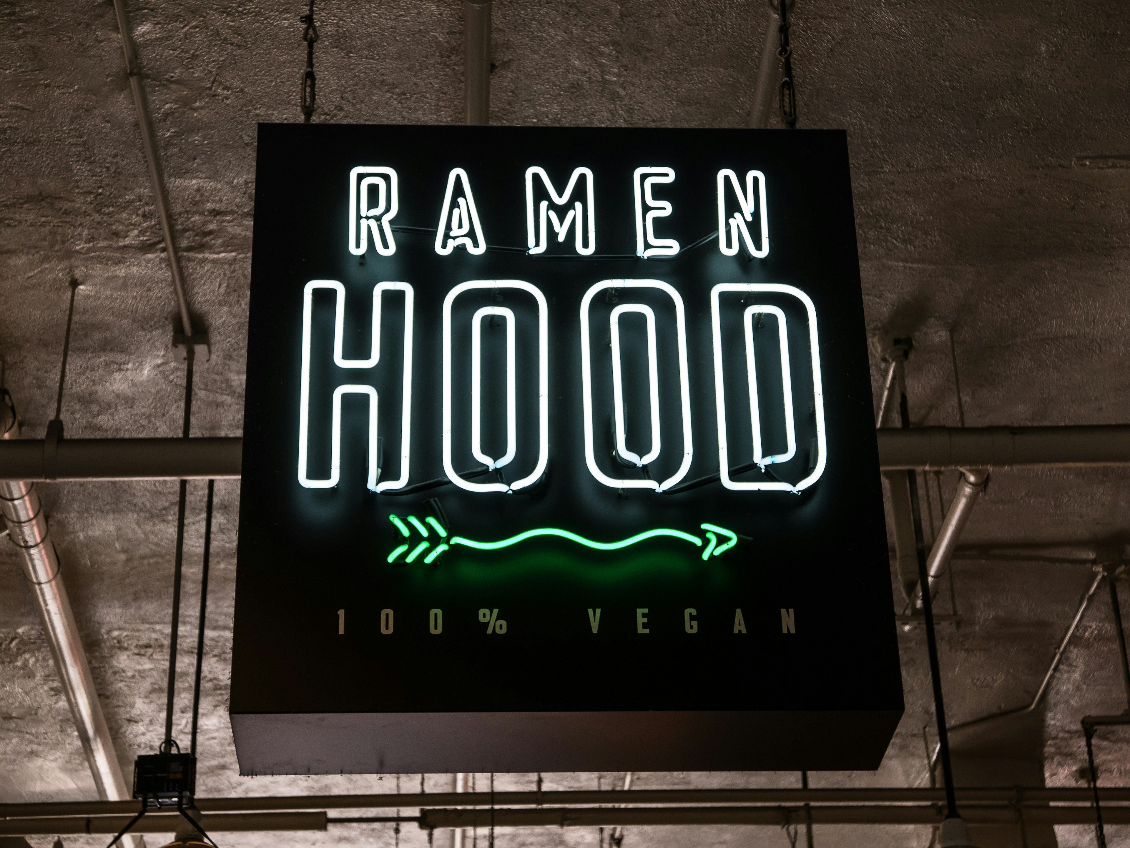 Neon sign with the words 'Ramen Hood' hangs from a ceiling; LA vegan restaurants