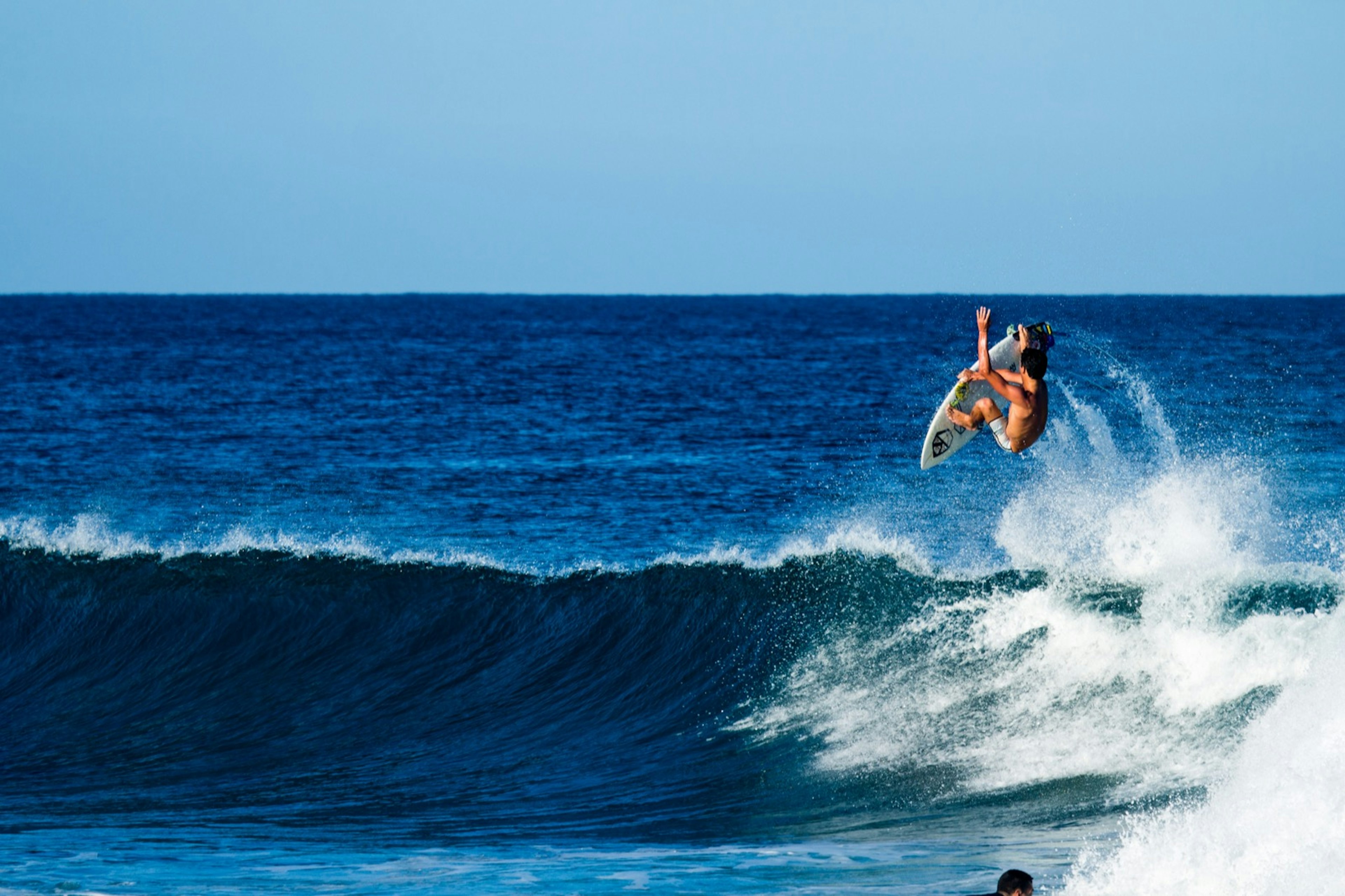 A surfer captured in the middle of an air-born rotation above a wave