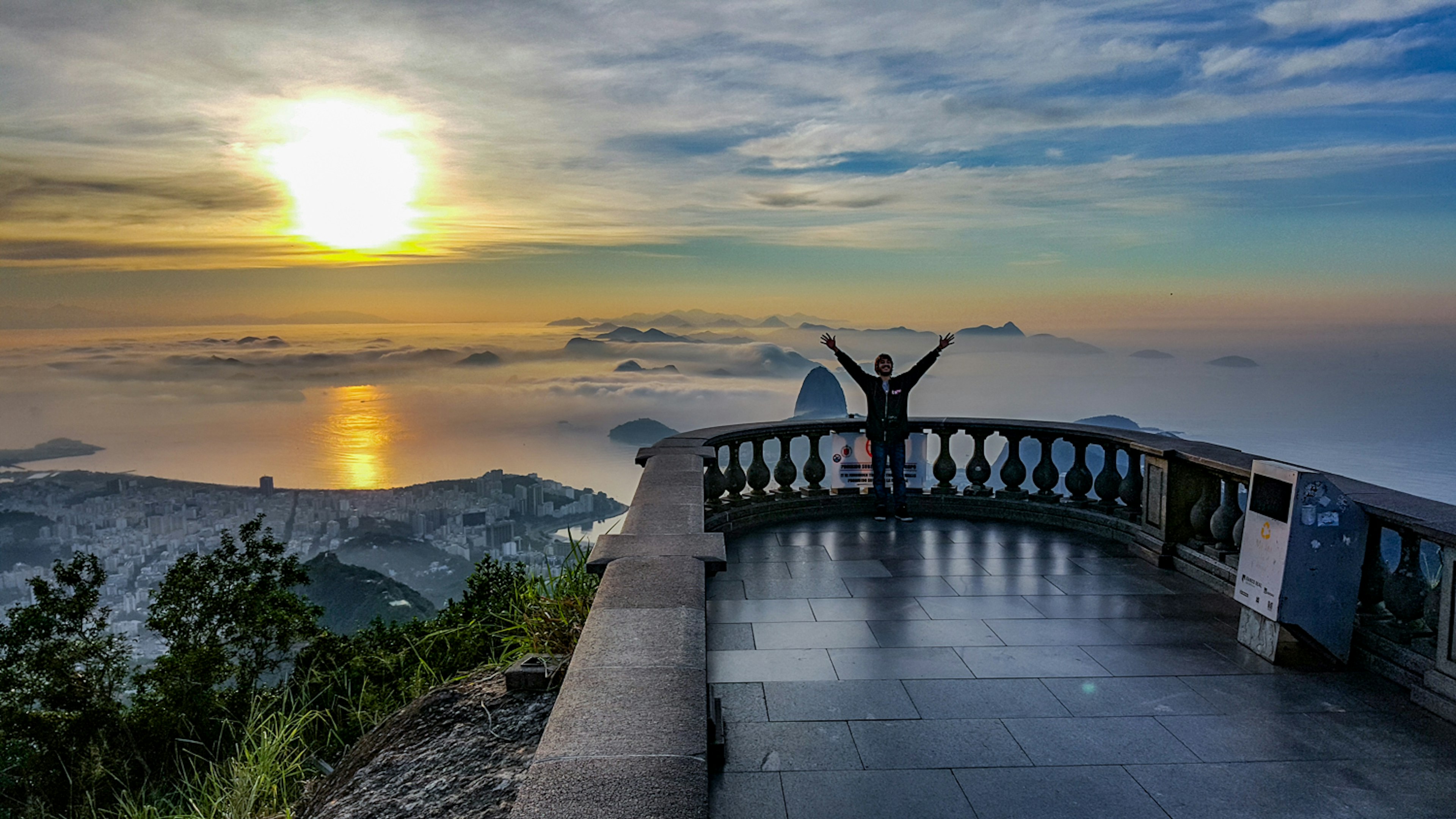 A man poses on a look-out platform with a sunset over the waters off the coast of Rio in the background © Tom Le Mesurier / ϰϲʿ¼