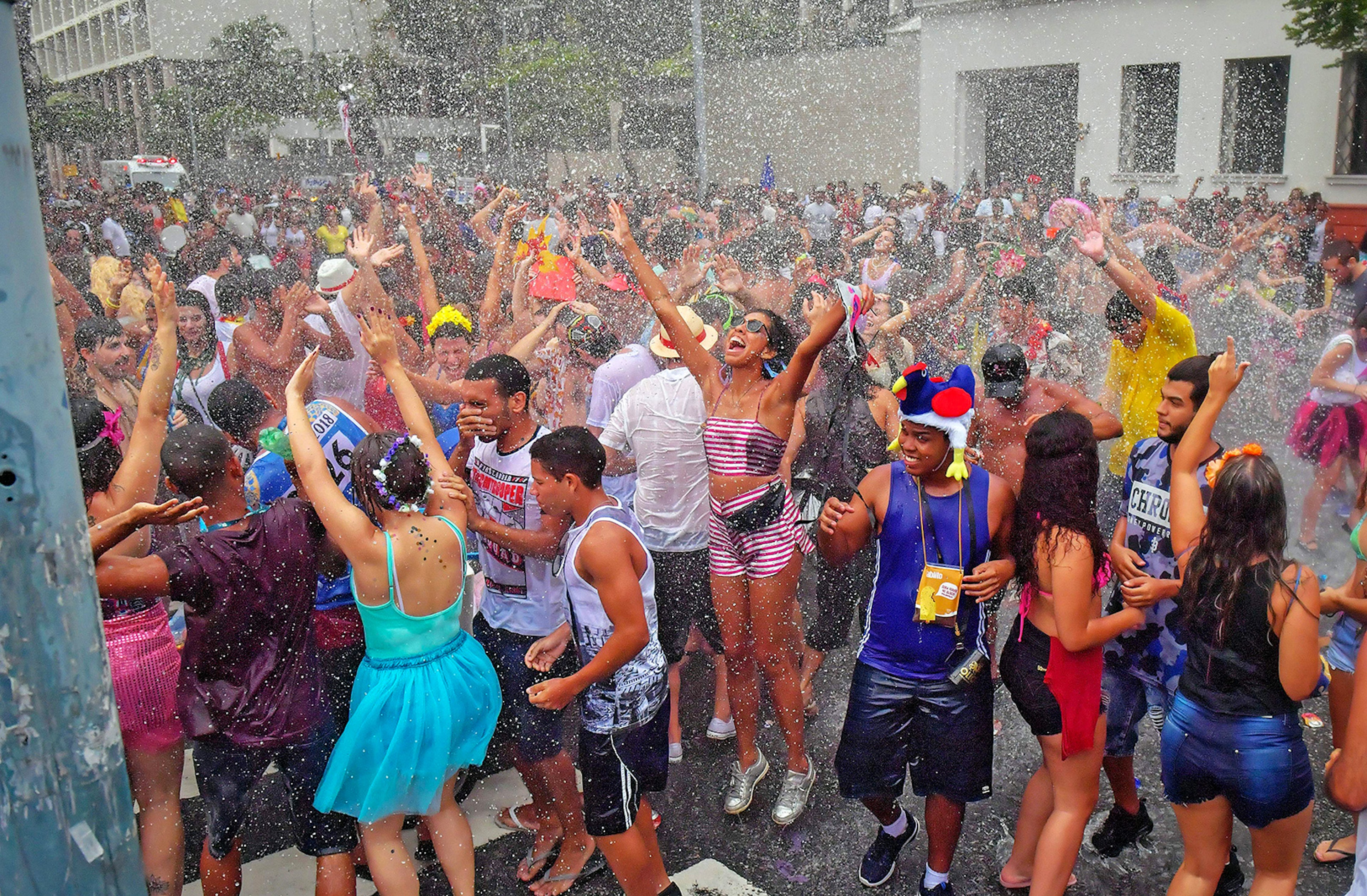 A group of people dance in the street while getting sprayed with water