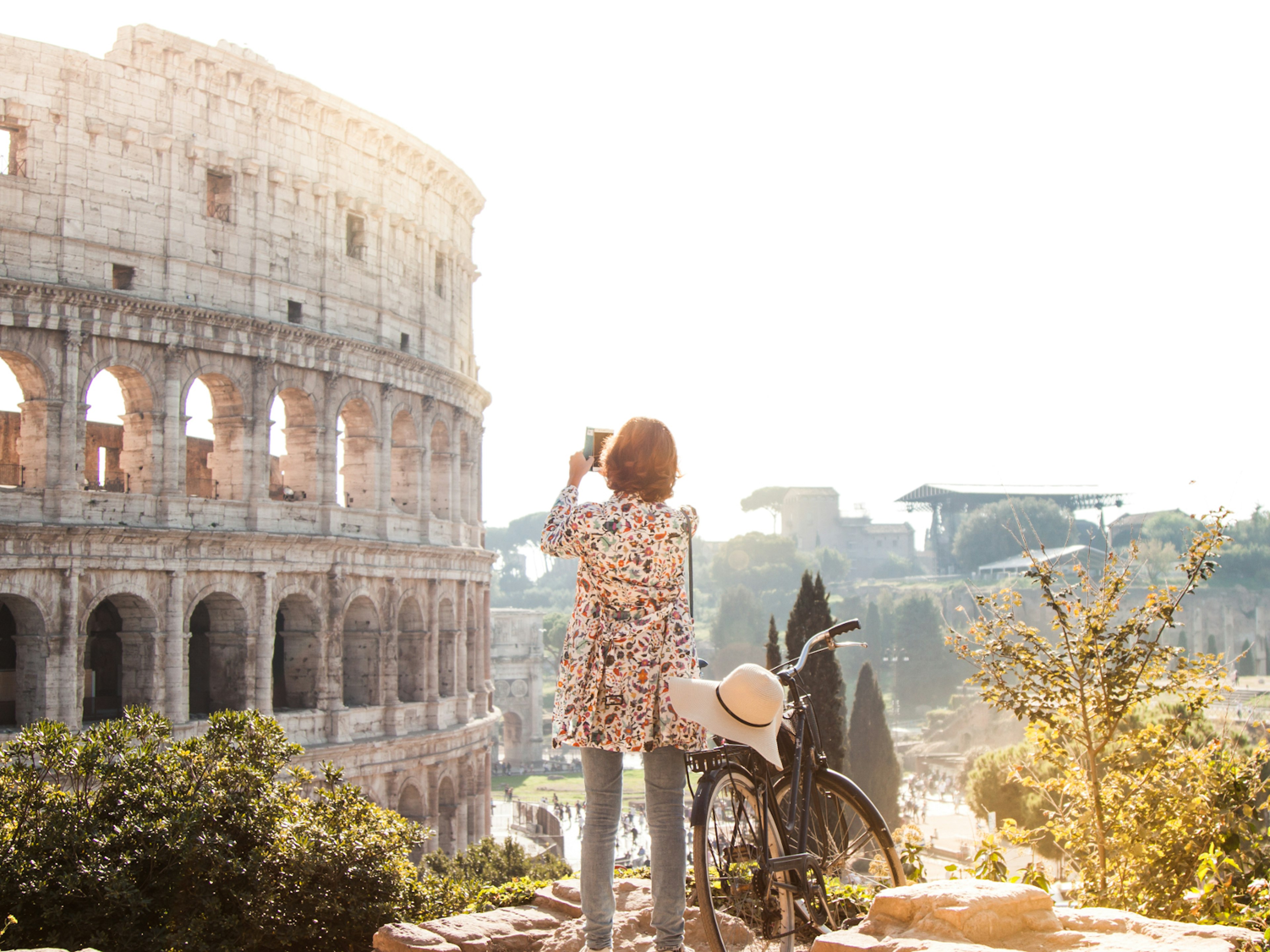 A woman takes a photo of the Colosseum in Rome