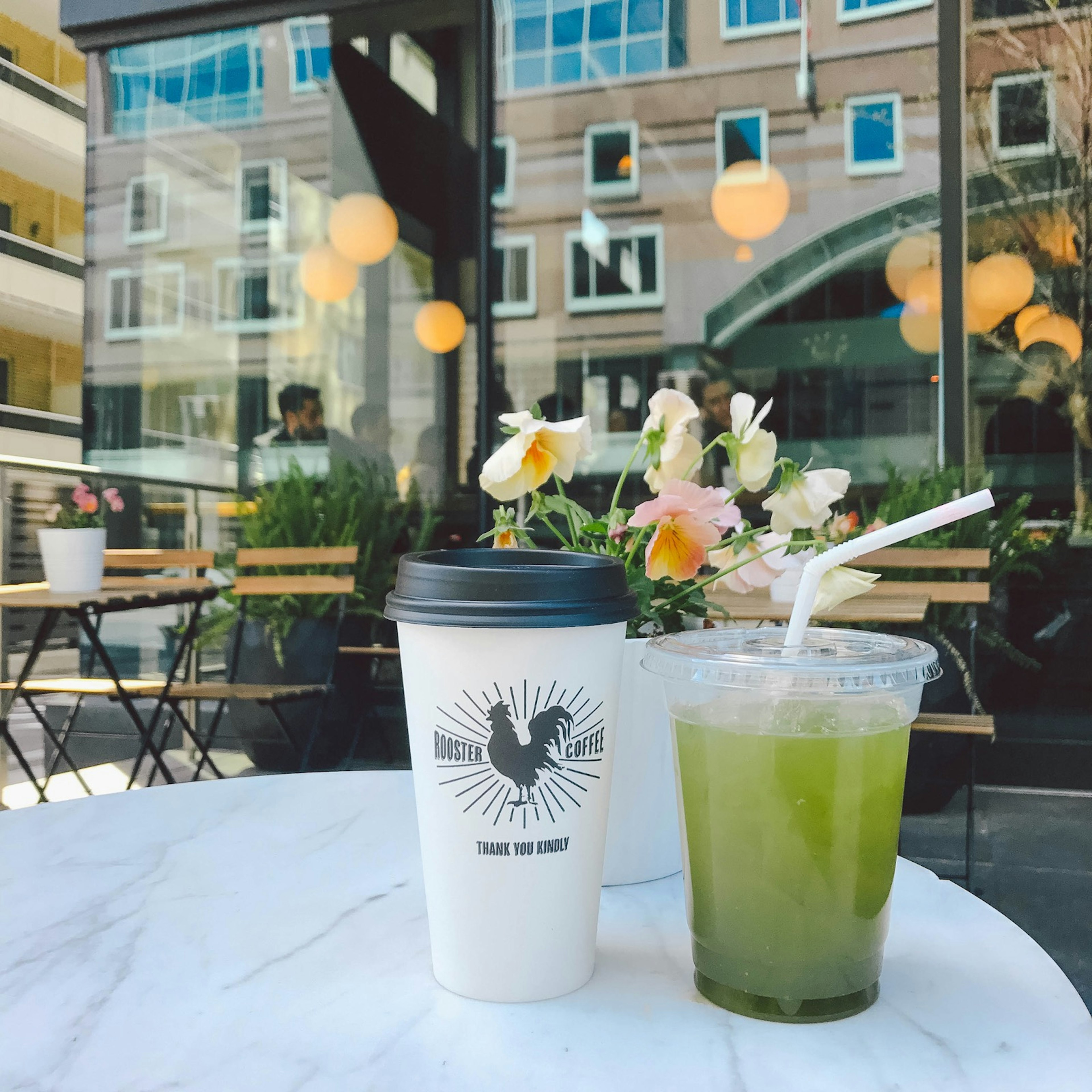 A green tea and tall black and white cup of coffee sit on a table with a Toronto street scene reflected in the window behind © Jessica Lam / ϰϲʿ¼