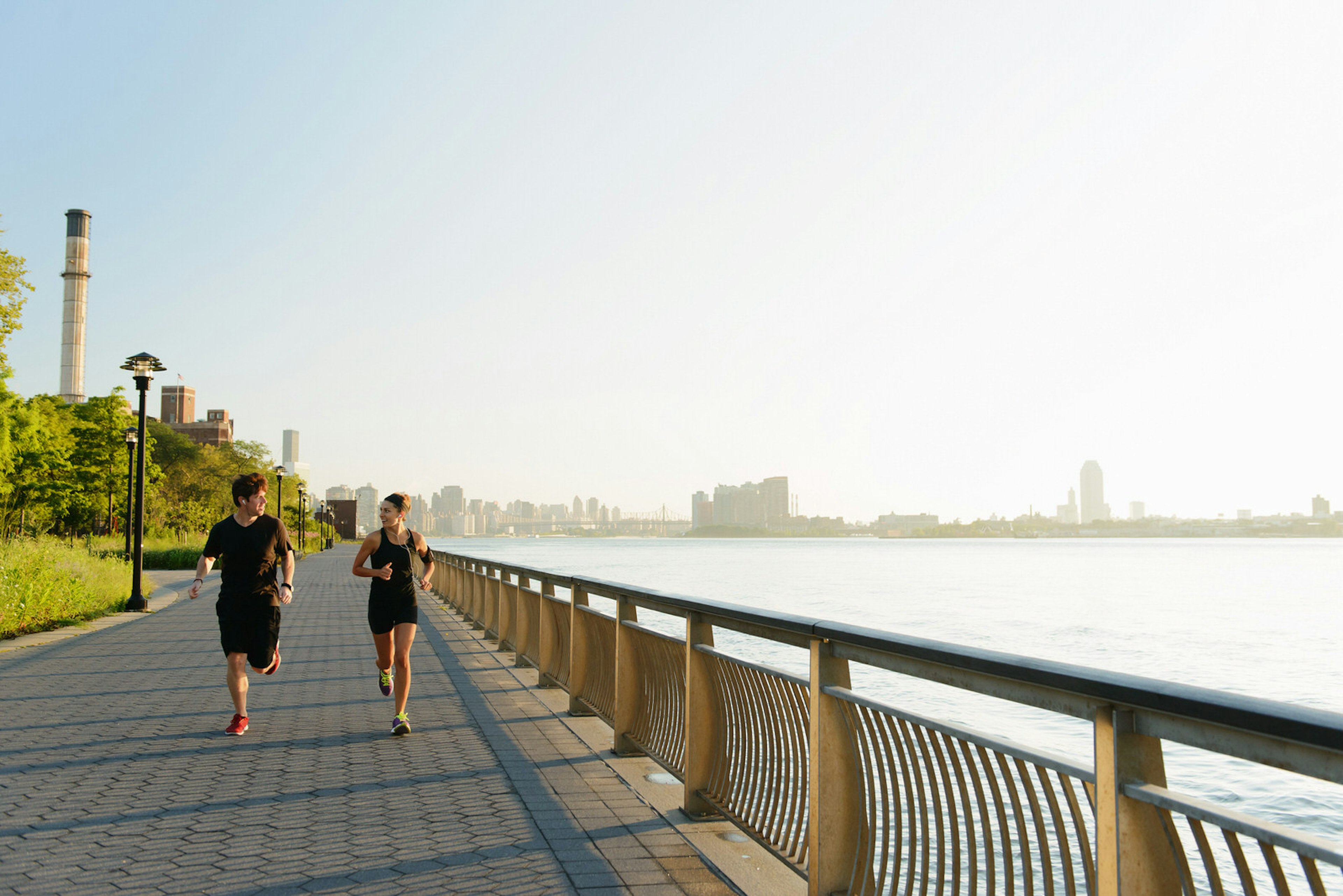 Two runners run along the footpath next to the Hudson River in New York City at twilight