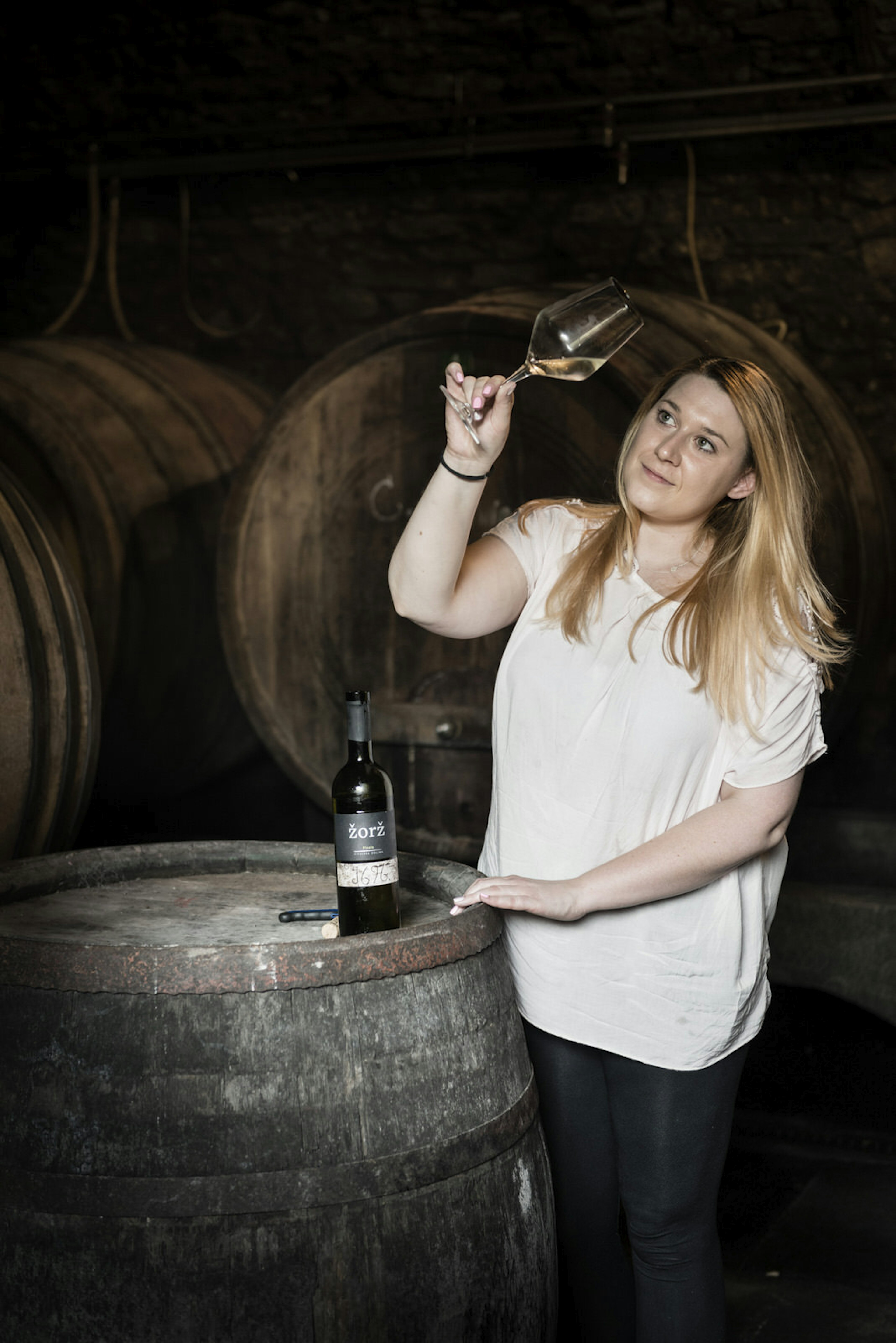 A woman holds a glass of white wine up to the light at Žorž © Justin Foulkes / Lonely Planet