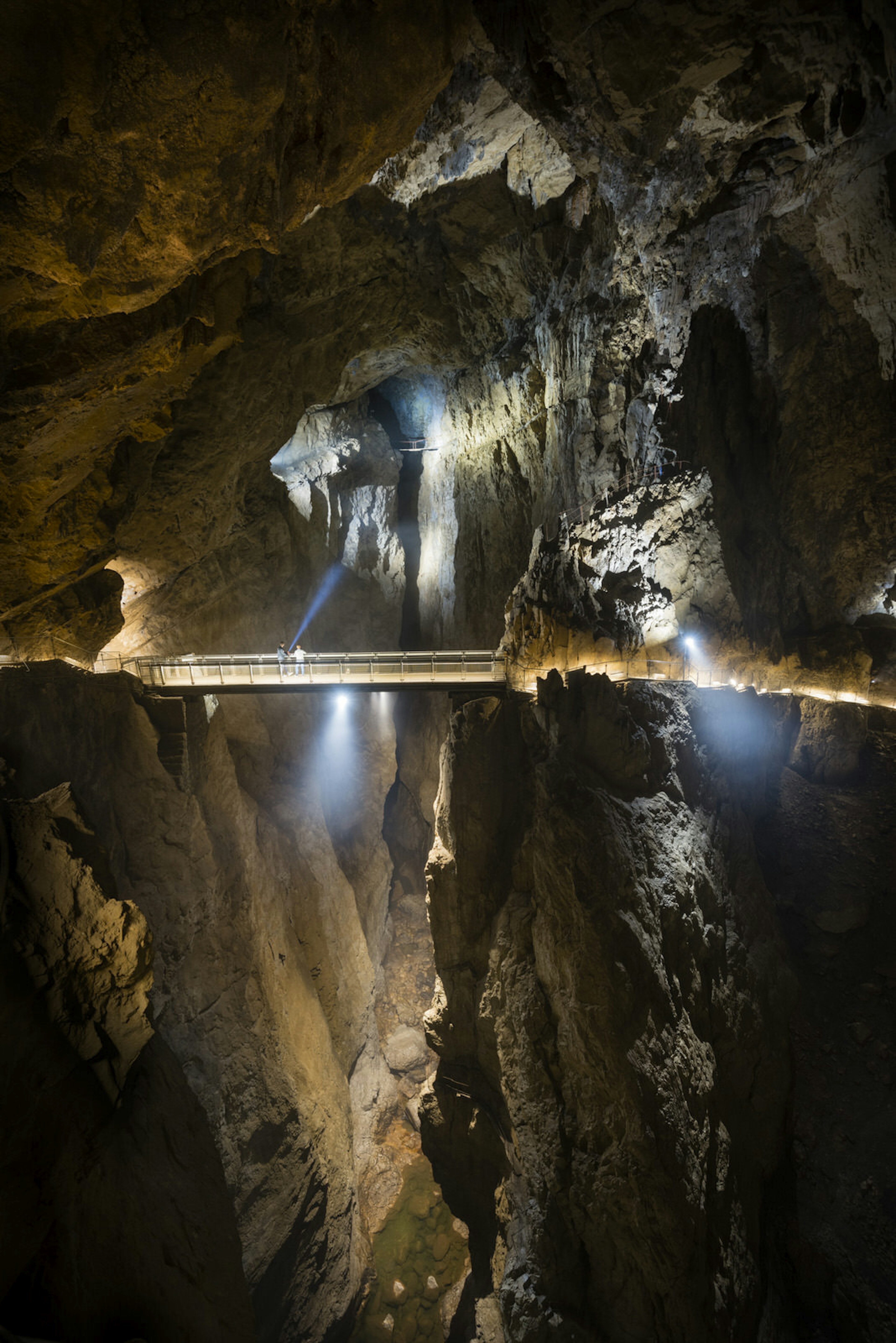 Two people stand on a narrow bridge, dwarfed by the huge chasm around them © Justin Foulkes / Lonely Planet