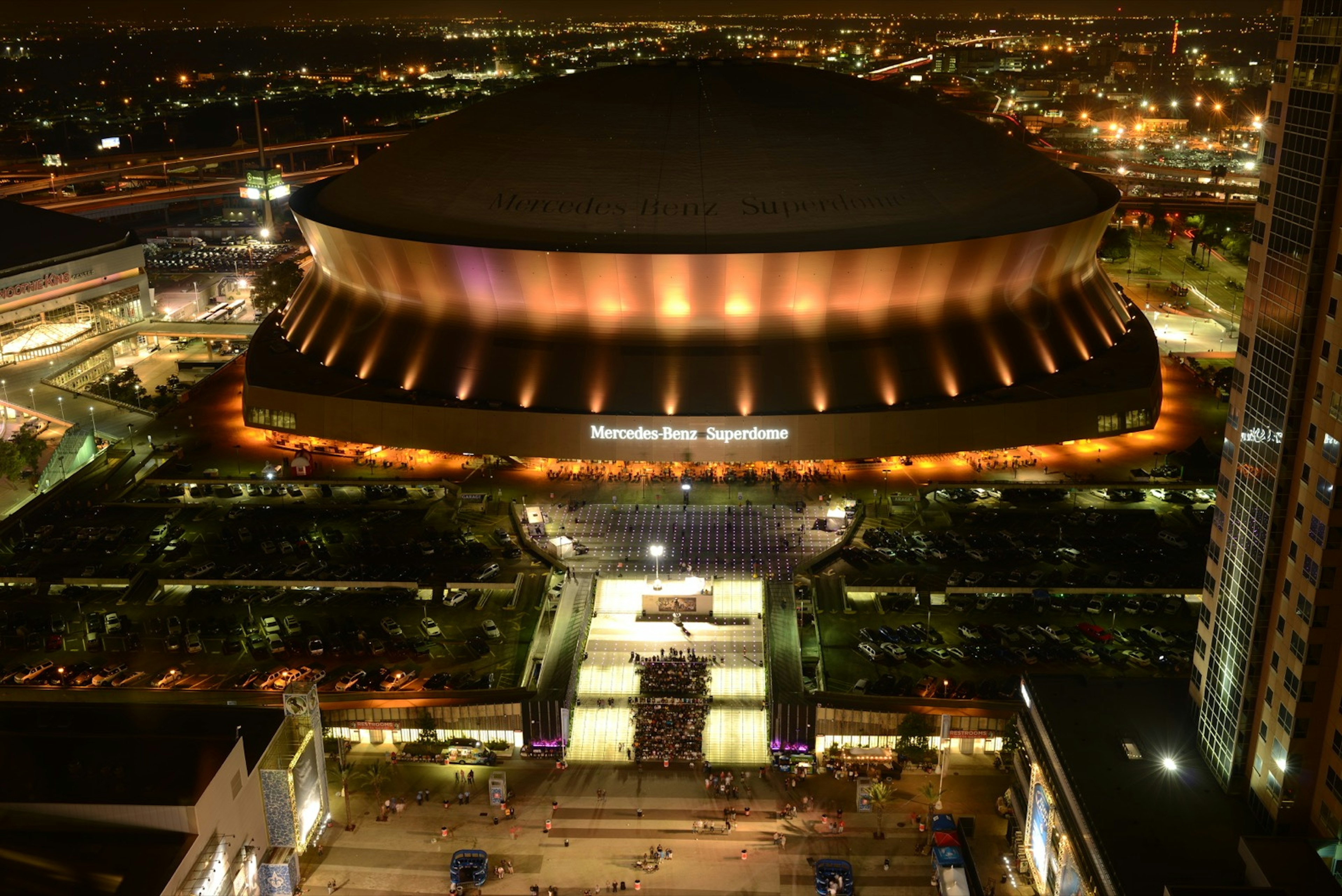 Overview shot of Mercedes Benz Stadium, home of the NFL's New Orleans Saints, glowing at night; nfl cities travel