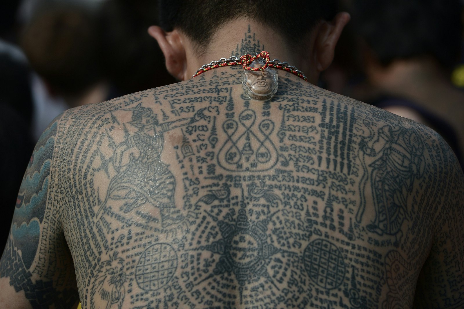 A heavily tattooed Buddhist devotee sits among the crowd during an annual tattoo festival, at Wat Bang Phra temple in Nakhon Chaisi west of Bangkok © Christophe Archambault / AFP / Getty Images