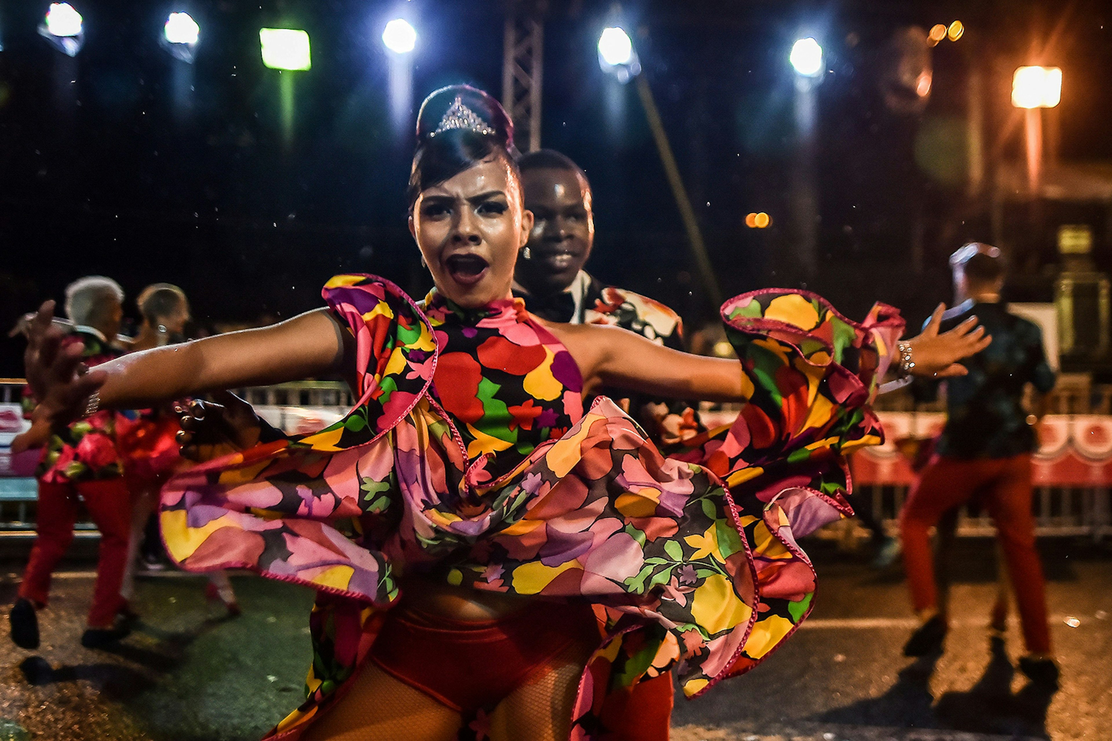 Two salsa dancers smile at the camera, while the female dancer twirls her skirt