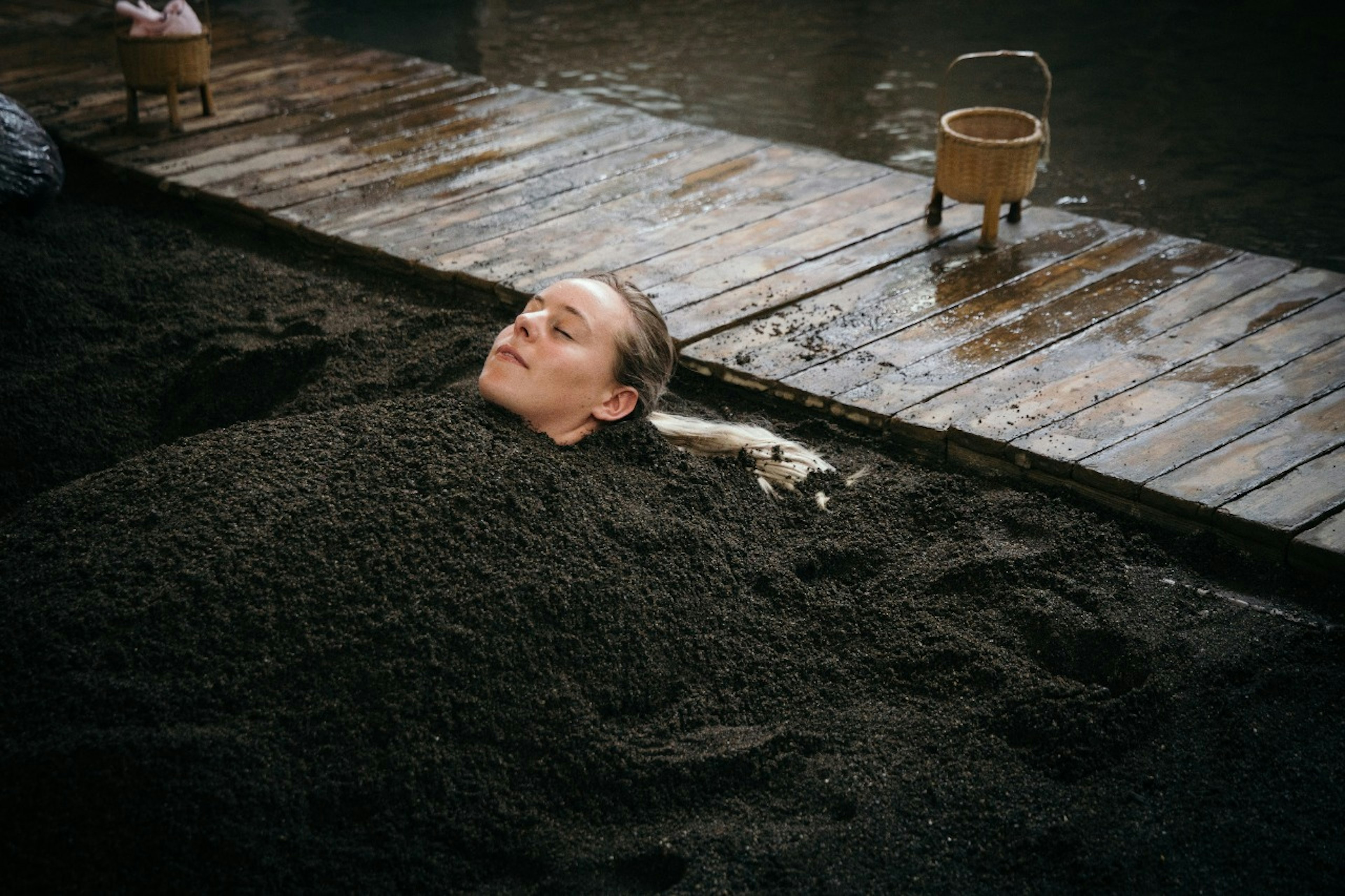 A woman enjoying a warm sand bath at Takegawara Onsen