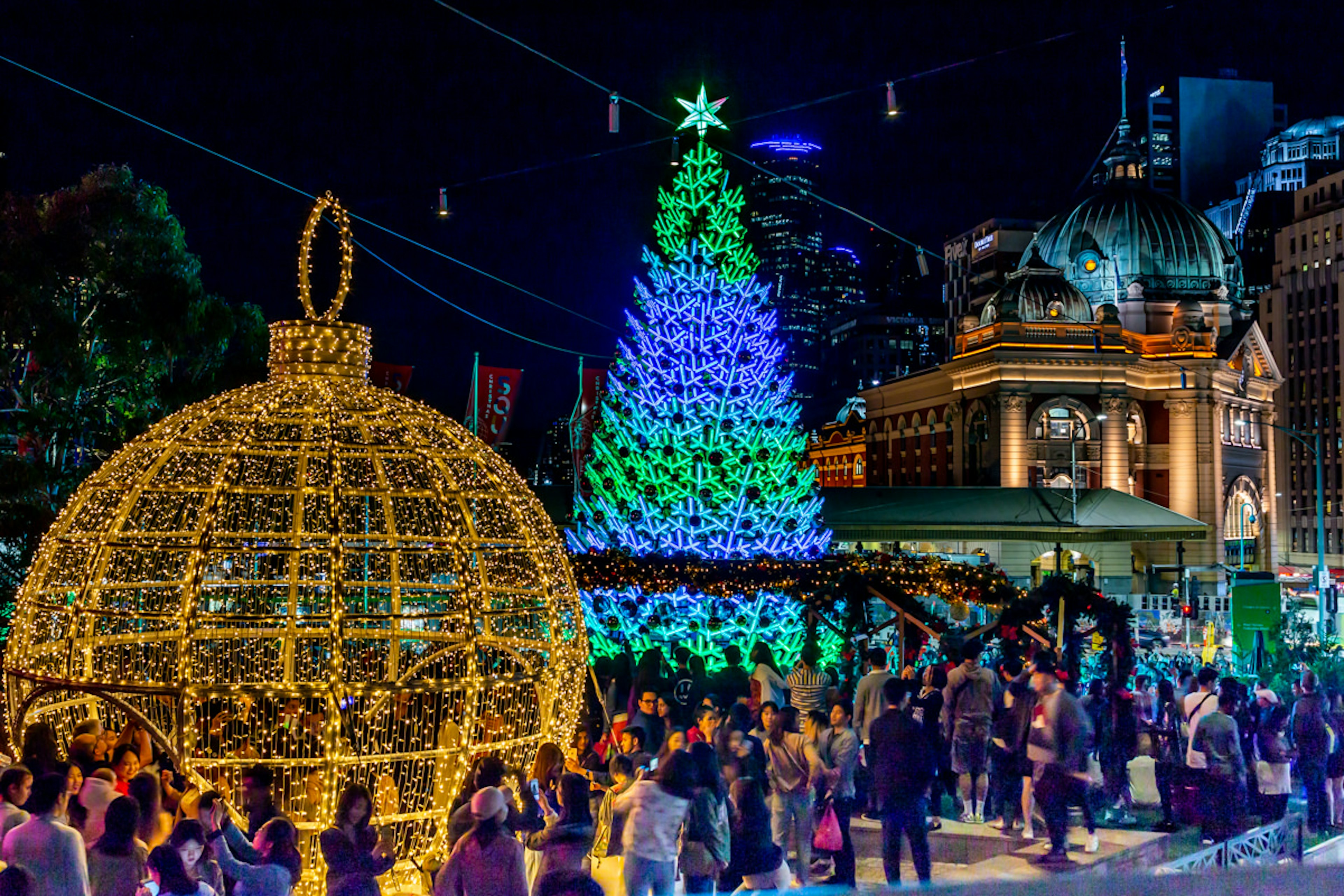 A shot of an ice rink surrounded by colourful Christmas objects made from fairy lights including a golden bauble and Christmas tree