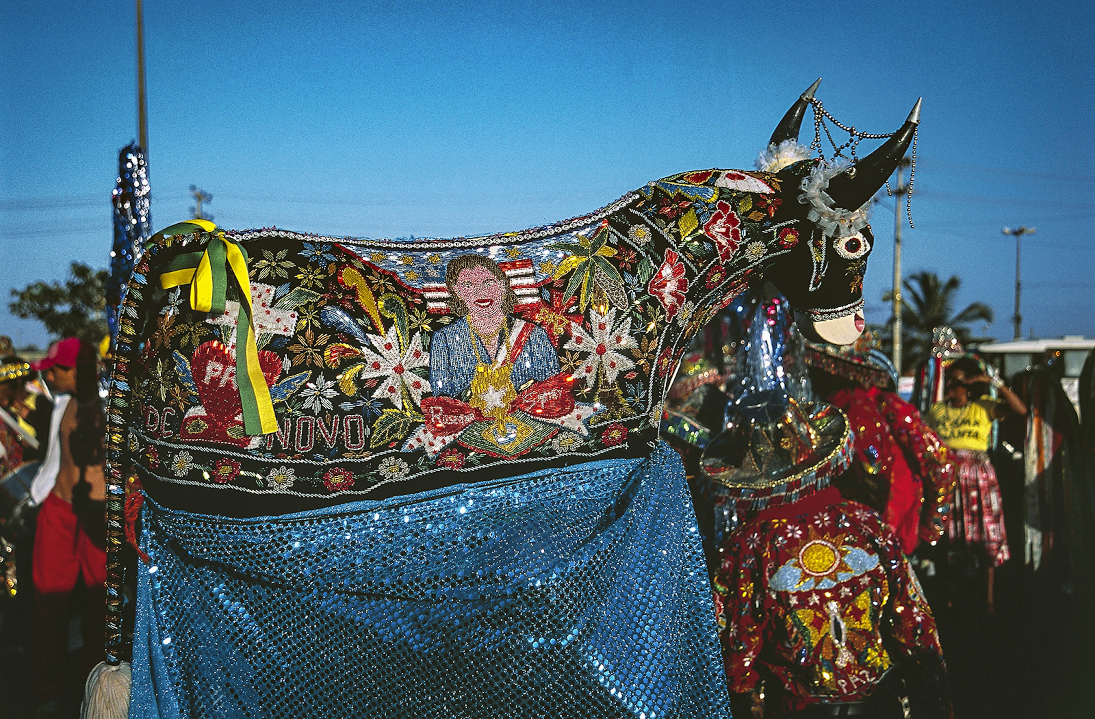 Costumed revellers in São Luís hold up an ox statue adorned in ribbons and sequins