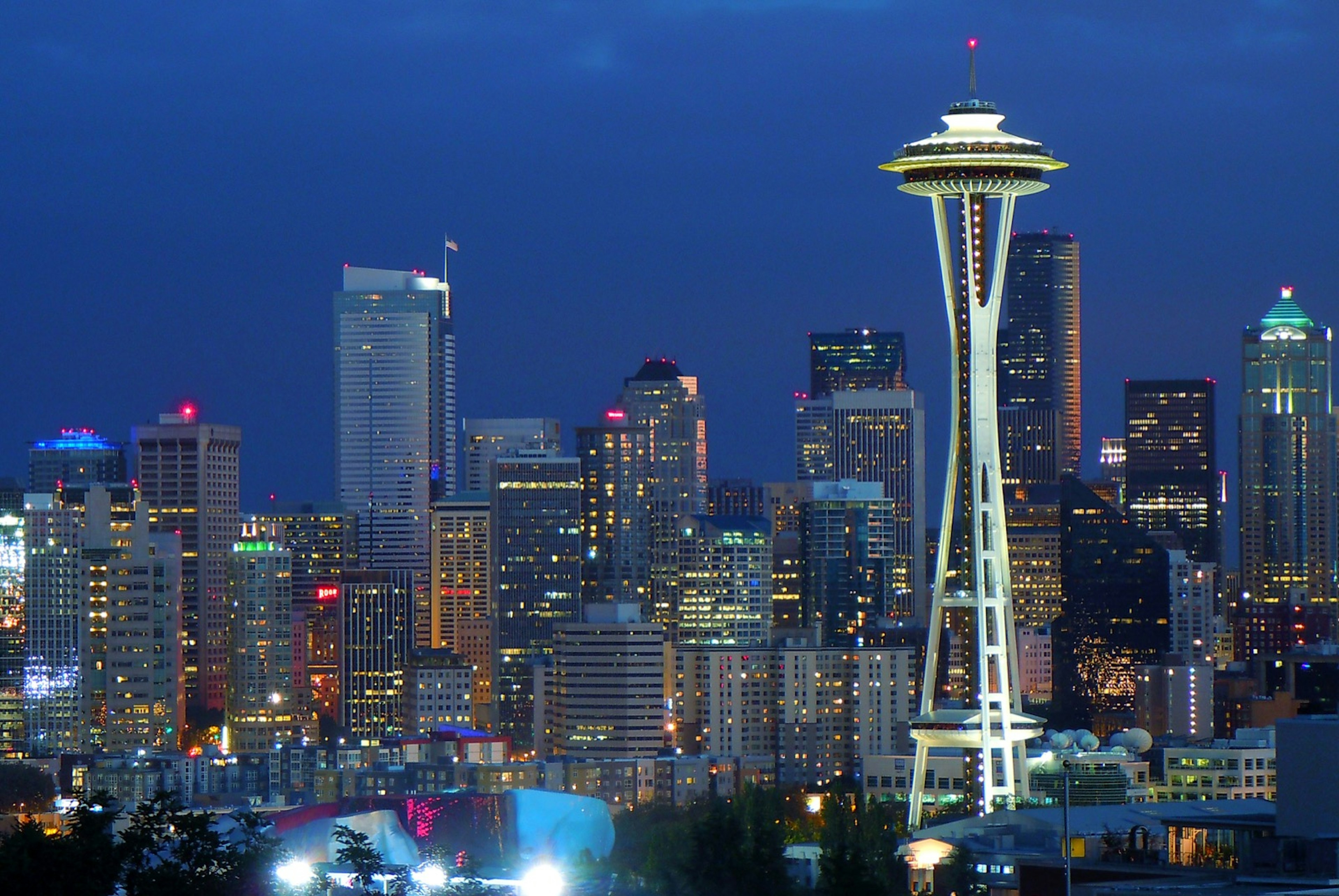 The skyline of seattle is seen in early evening, with lights on the space needle and various other buildings. Perfect weekend in Seattle