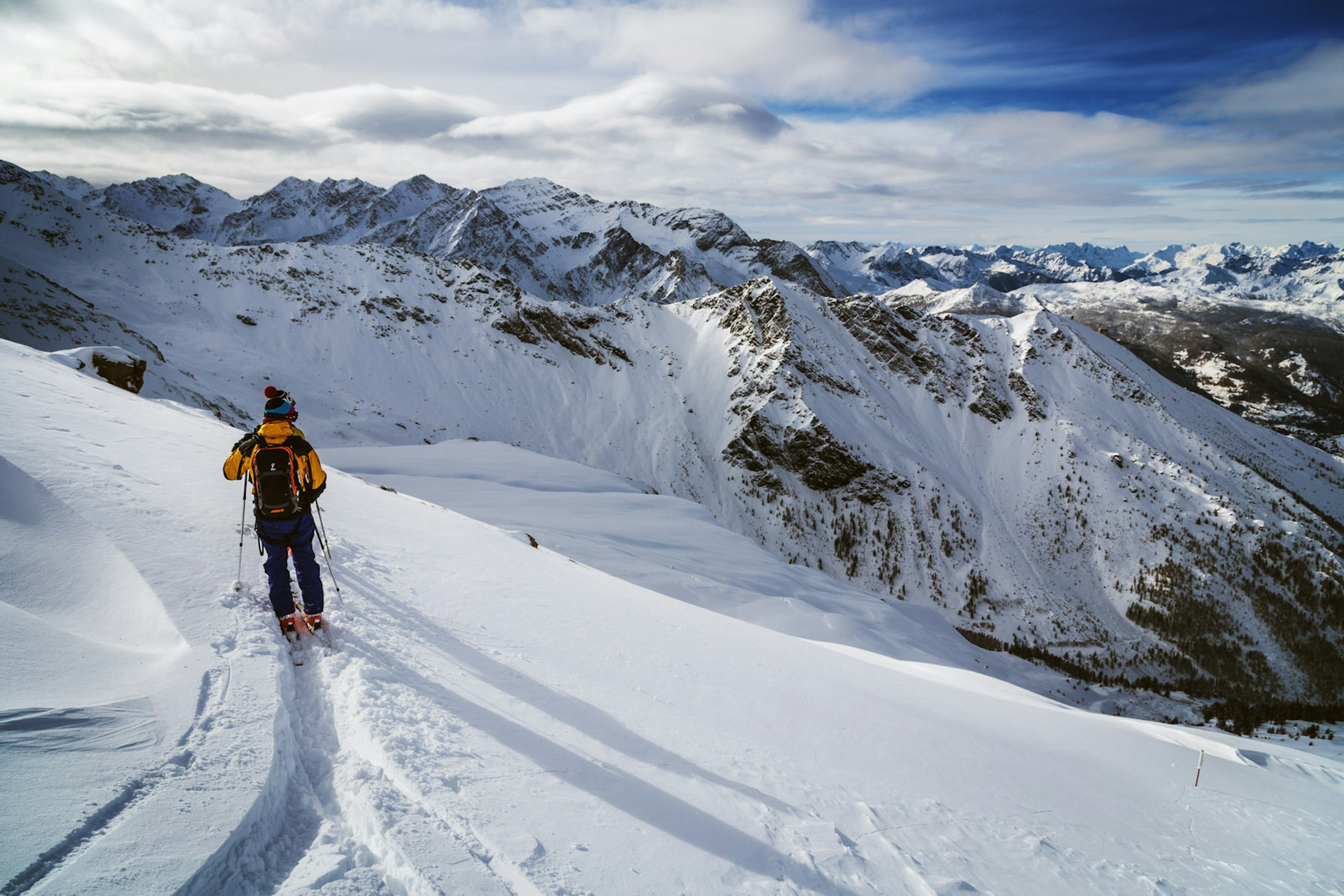 A skier poles through powdery snow in front of a dramatic mountain backdrop © Federico Ravassard / Getty Images