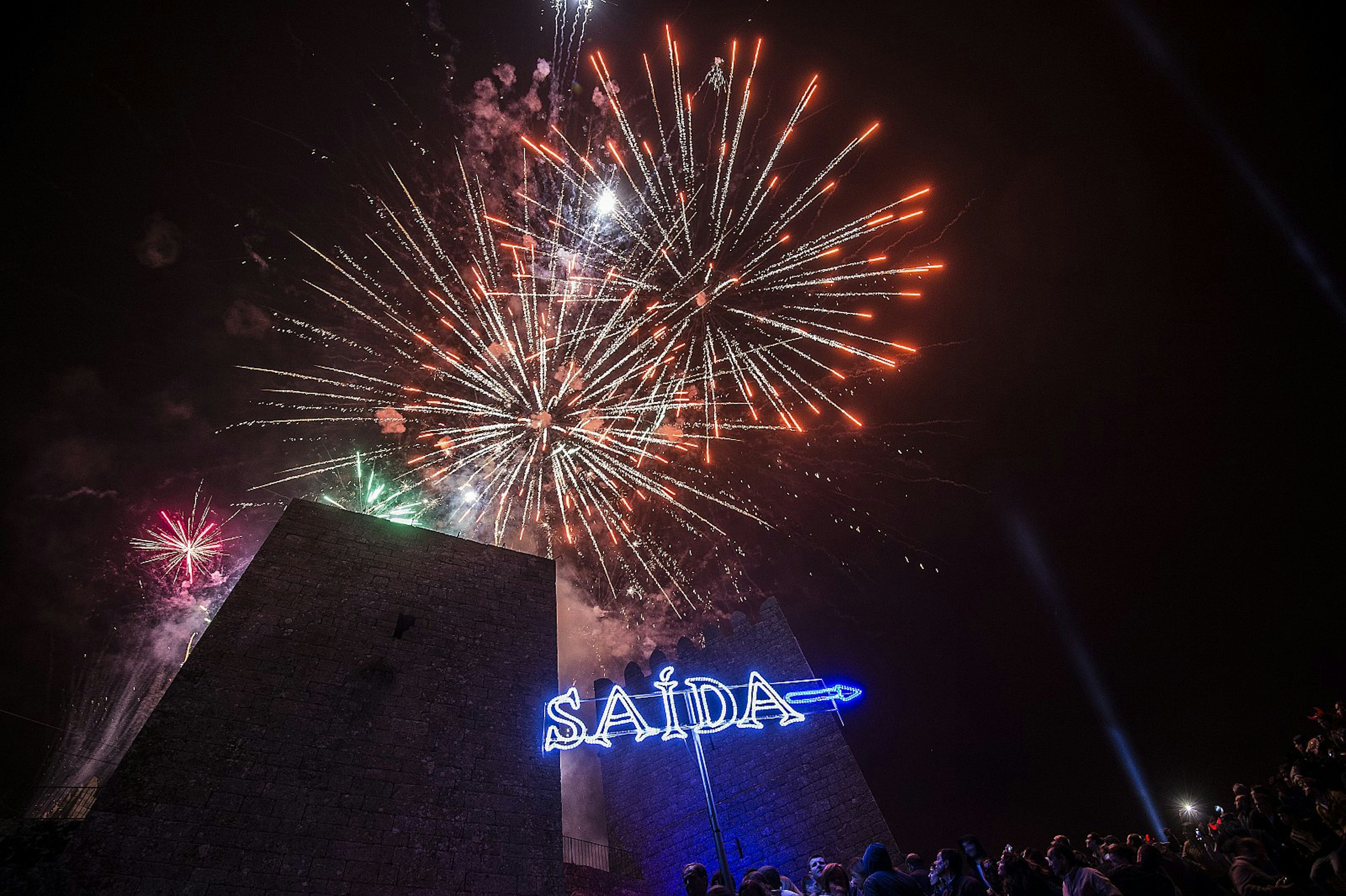 Fireworks lighting up the sky at the Sexta13 festival, above a neon