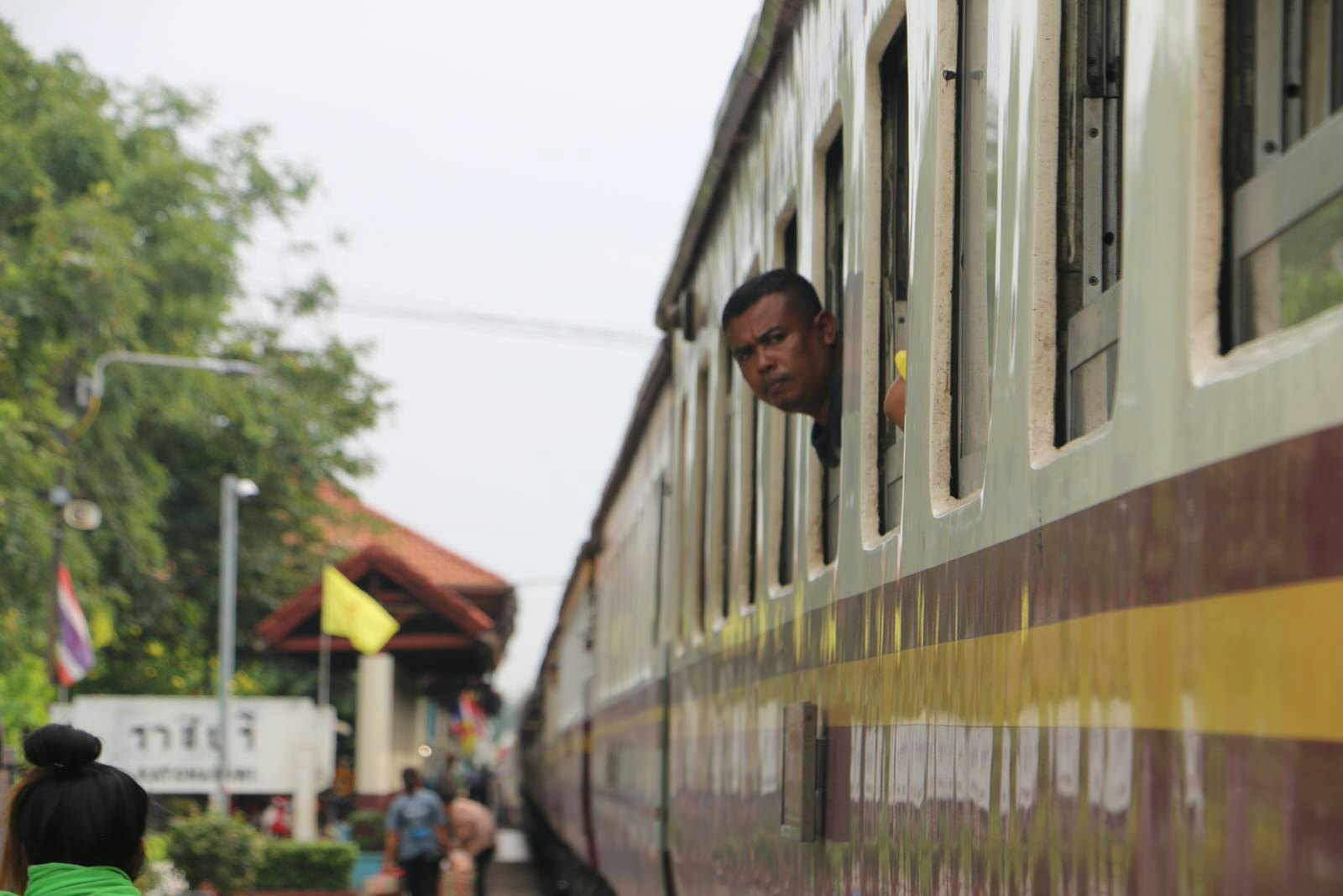 A man peeps his head out of a train window en route to Bangkok