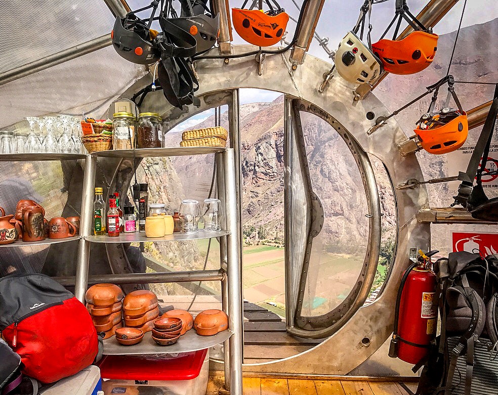 A head-on view of a circular door in a transparent capsule; a valley floor is visible through the doorway