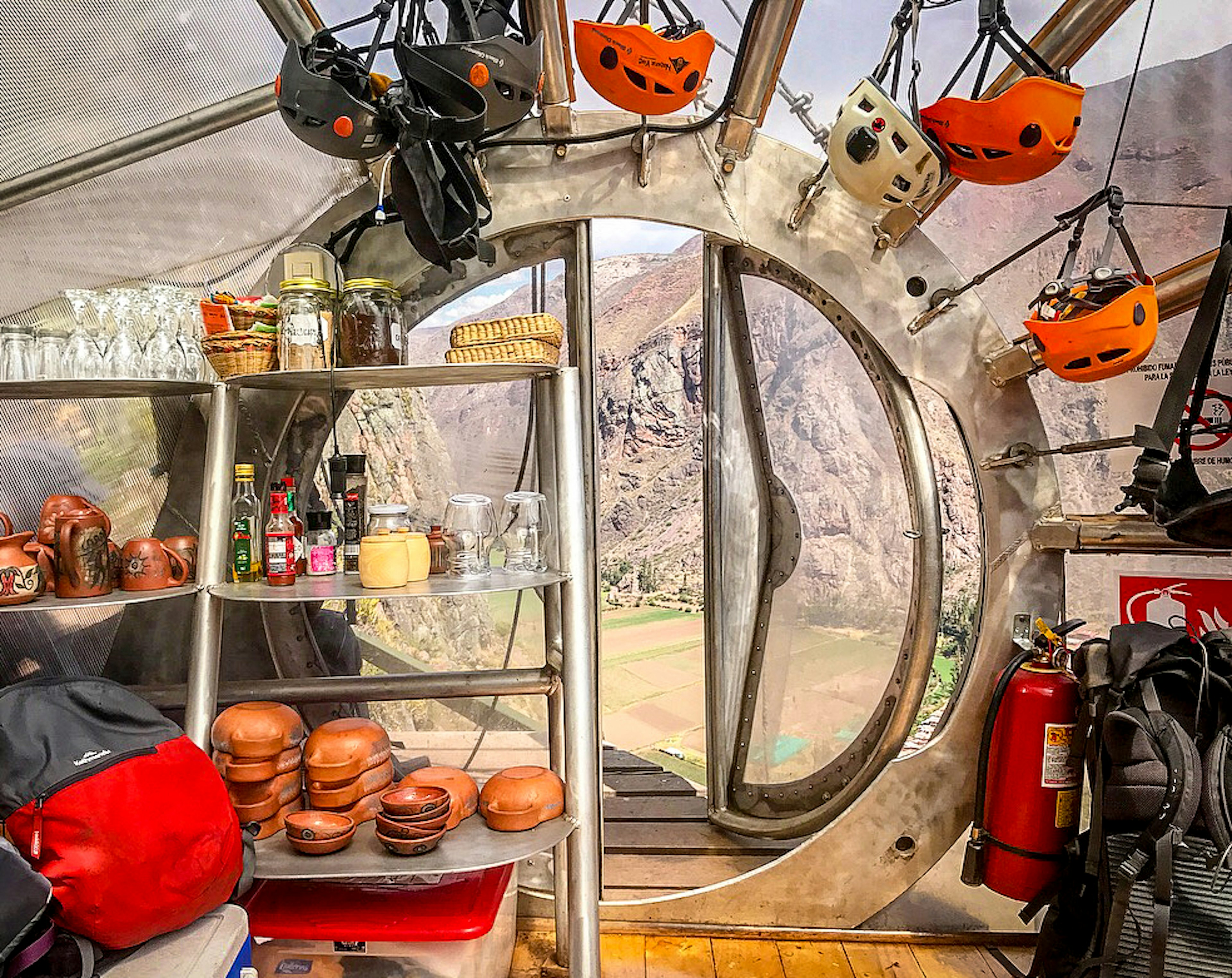 A head-on view of a circular door in a transparent capsule; a valley floor is visible through the doorway