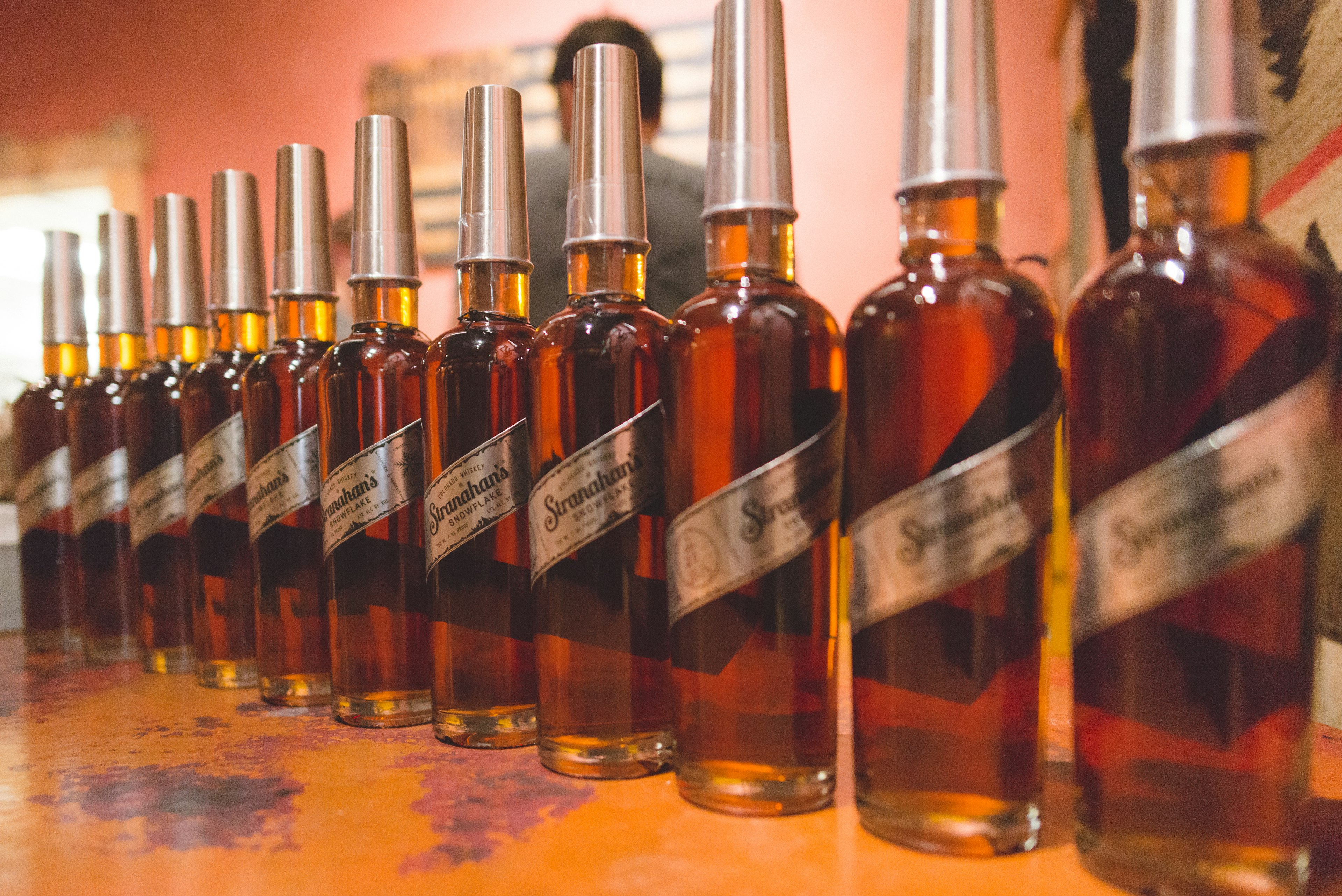 A row of glass bottles filled with amber-colored whiskey sit on counter at Stranahan's