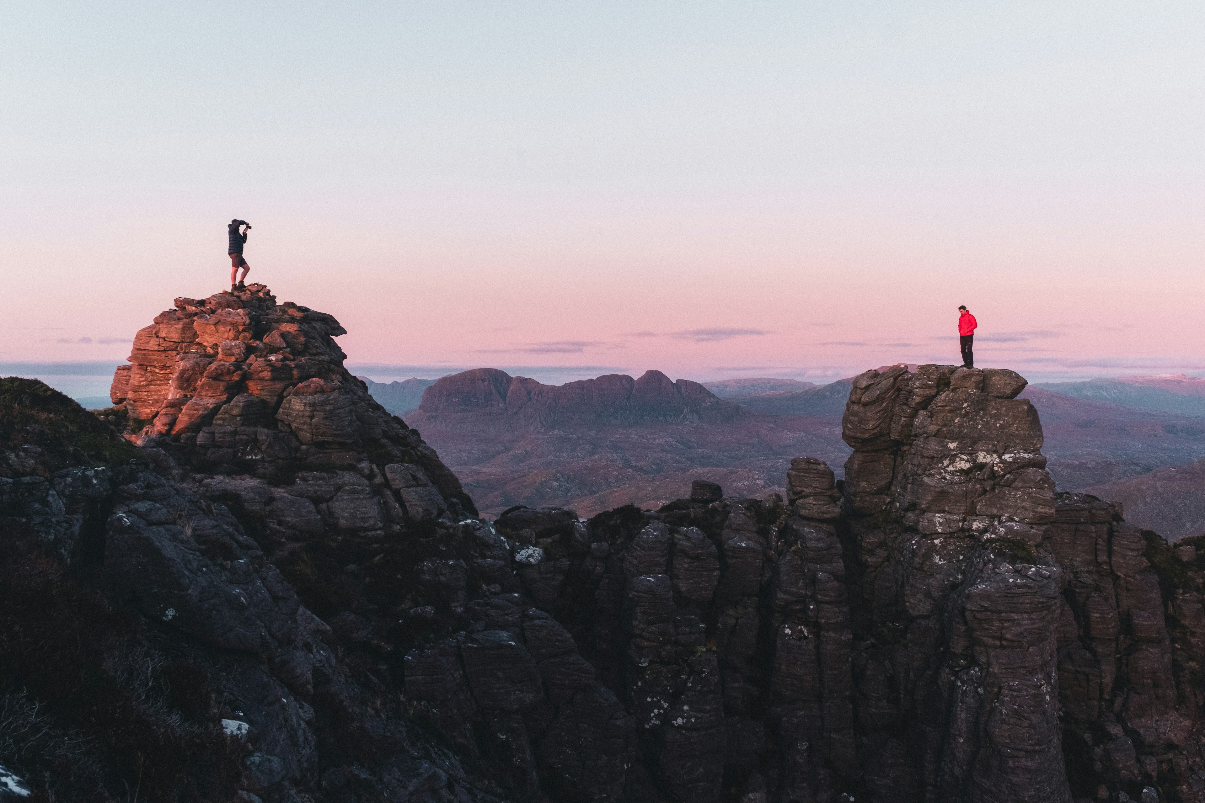 Stach Pollaidh at sunset, with two men standing on separate peaks.