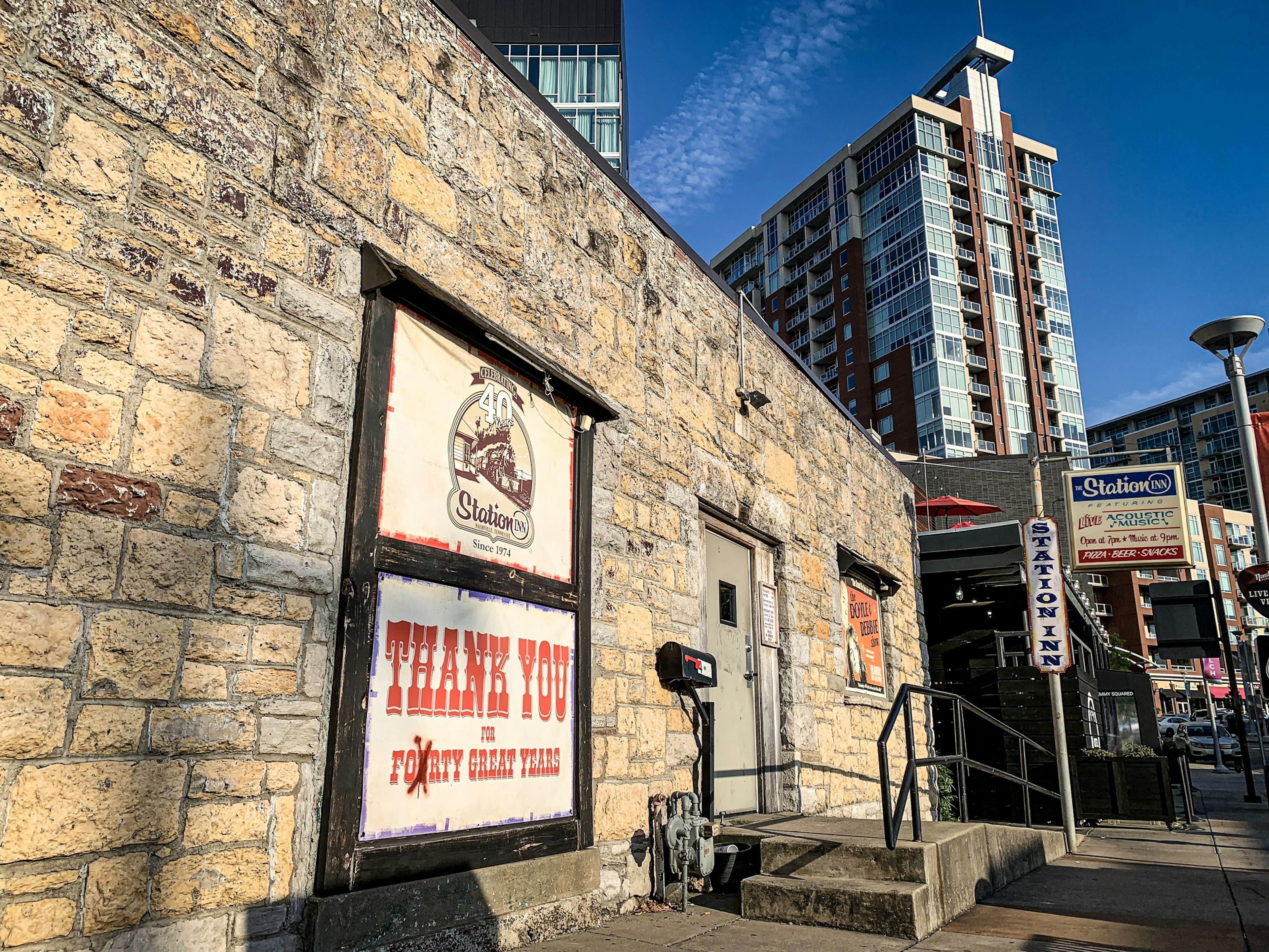 A small stone building marked as the Station Inn is surrounded by high-rises; best country music venues in Nashville