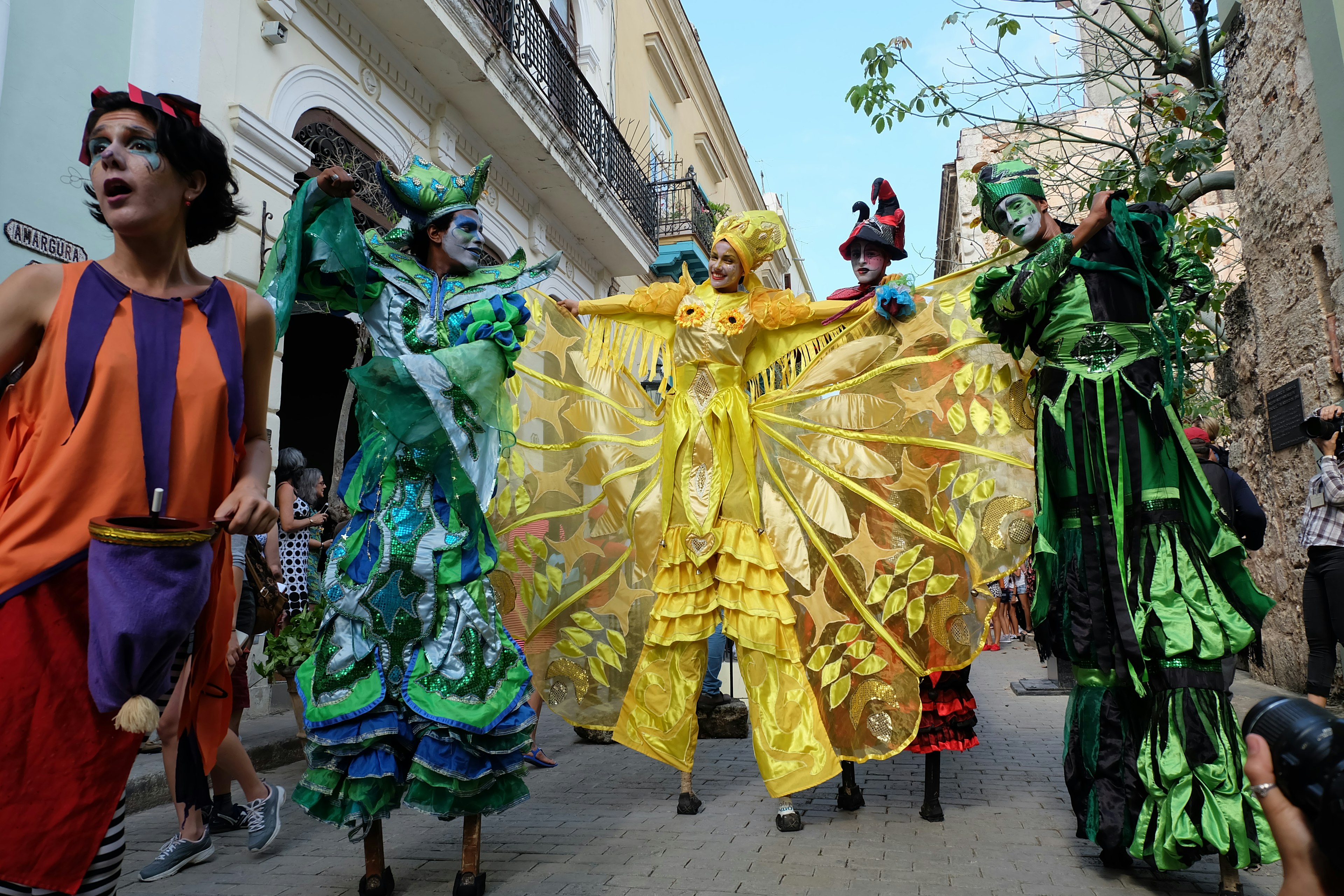 A group of stilt walkers head down old Havana in elaborate bright costumes; Havana anniversary