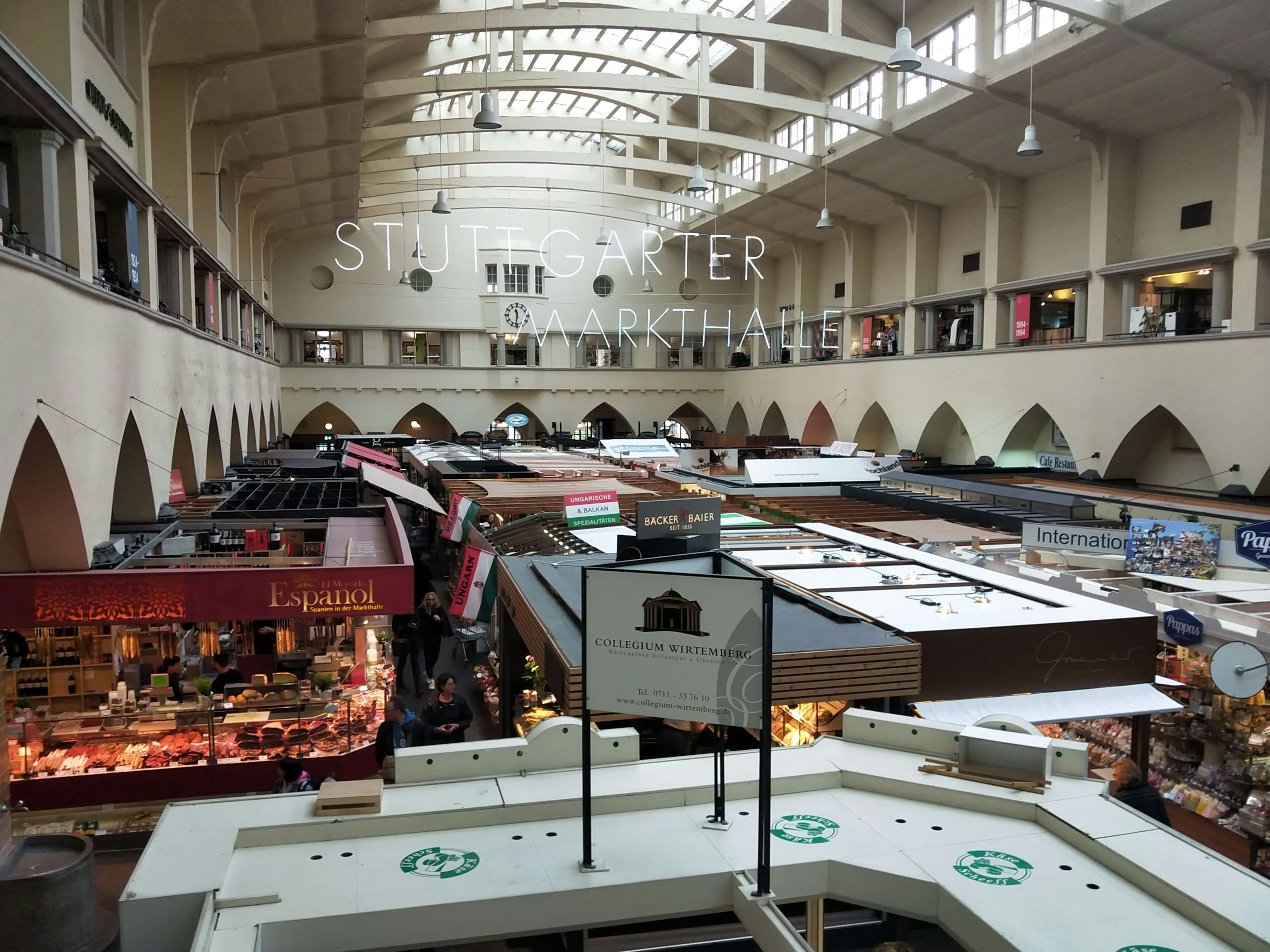 View from a gallery inside a market hall, looking down on many food stalls. Individual white letters spelling out