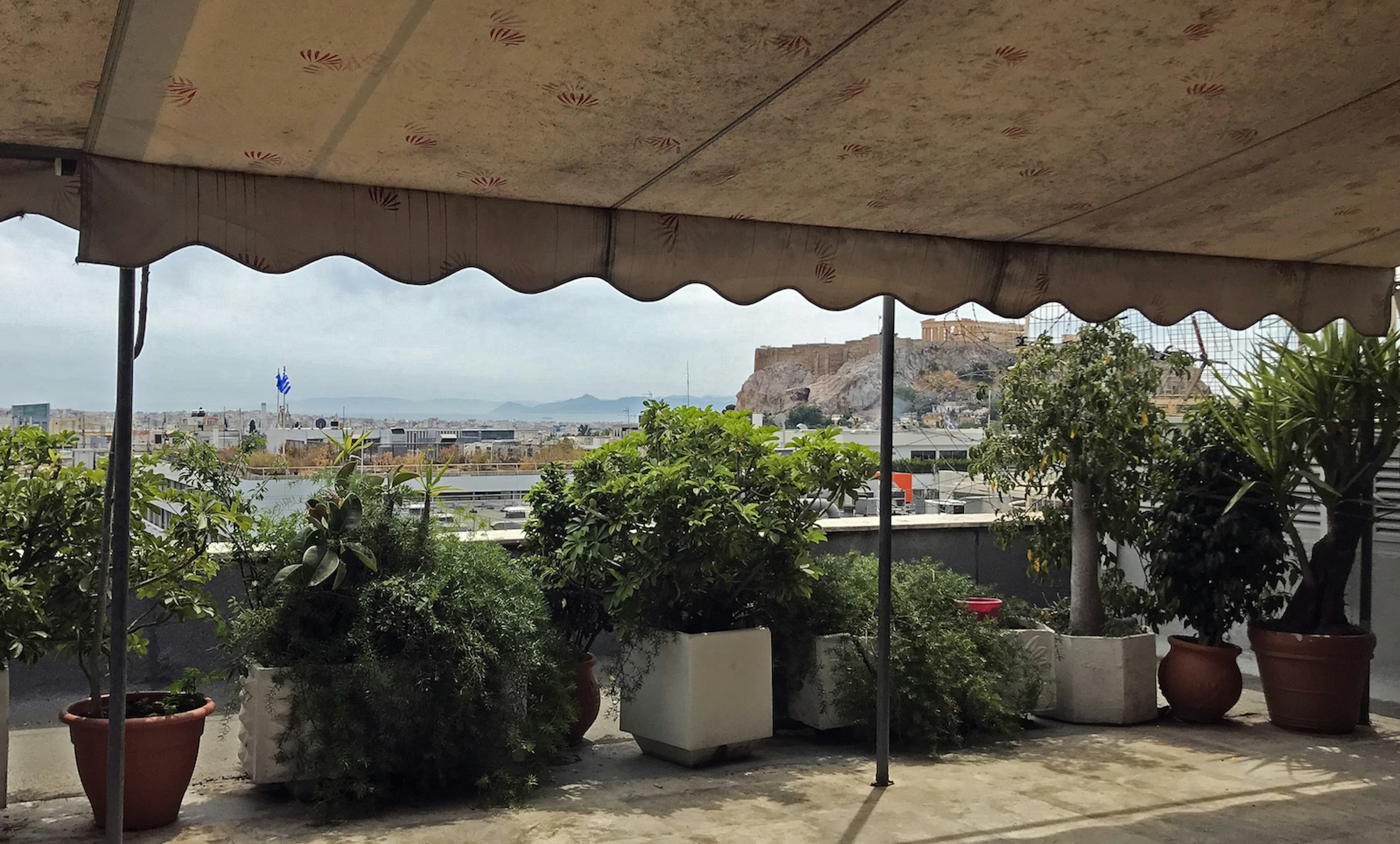 The view from the Syntagma Kantina patio, a blue sky and the Acropolis rock in the background